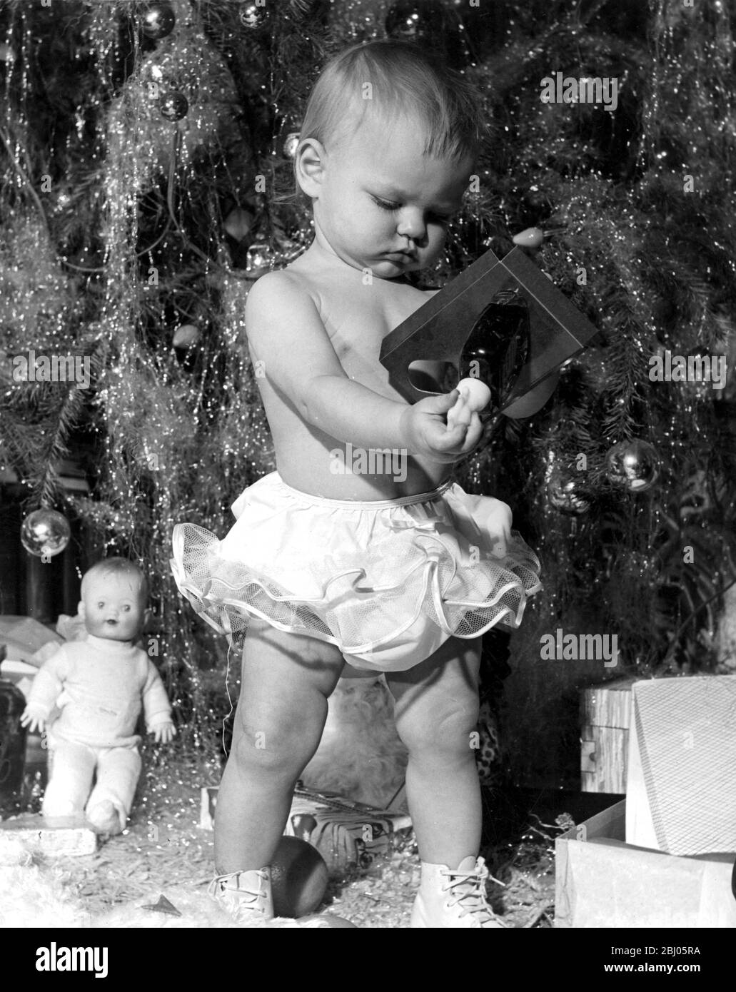 Kleinkind Untersuchung Spielzeug unter dem Weihnachtsbaum Stockfoto