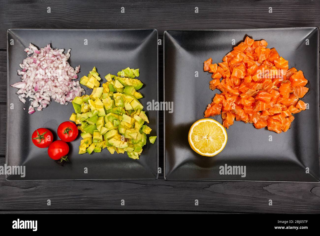 Scheiben Lachs, Zwiebel und Avocado auf Tellern auf schwarzem Holzhintergrund Stockfoto