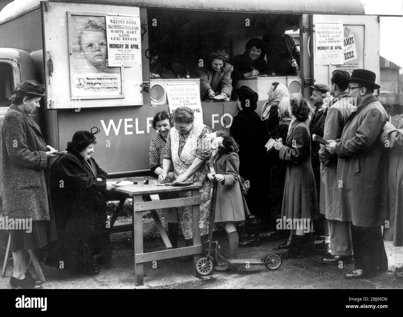 Ration Books get Mobile 1. Mai 1951......... - das erste mobile Lebensmittelbüro ging (Montag) in der White Hart Lane, Tottenham, in Betrieb, und anstatt Hausfrauen, die sich im Lebensmittelbüro für ihre Lebensmittellaken anstellen, kam das Büro in Form eines ordentlichen Van zu ihnen. FOTO ZEIGT : - Miss I Maguire (am Tisch) serviert Tottenham Hausfrauen mit ihren Rationsbüchern. Sie erhalten die Bücher und singen für sie. Miss Maguire ist Mitarbeiter des Tottenham Food Office. Das mobile Food Office ist im Hintergrund. Stockfoto