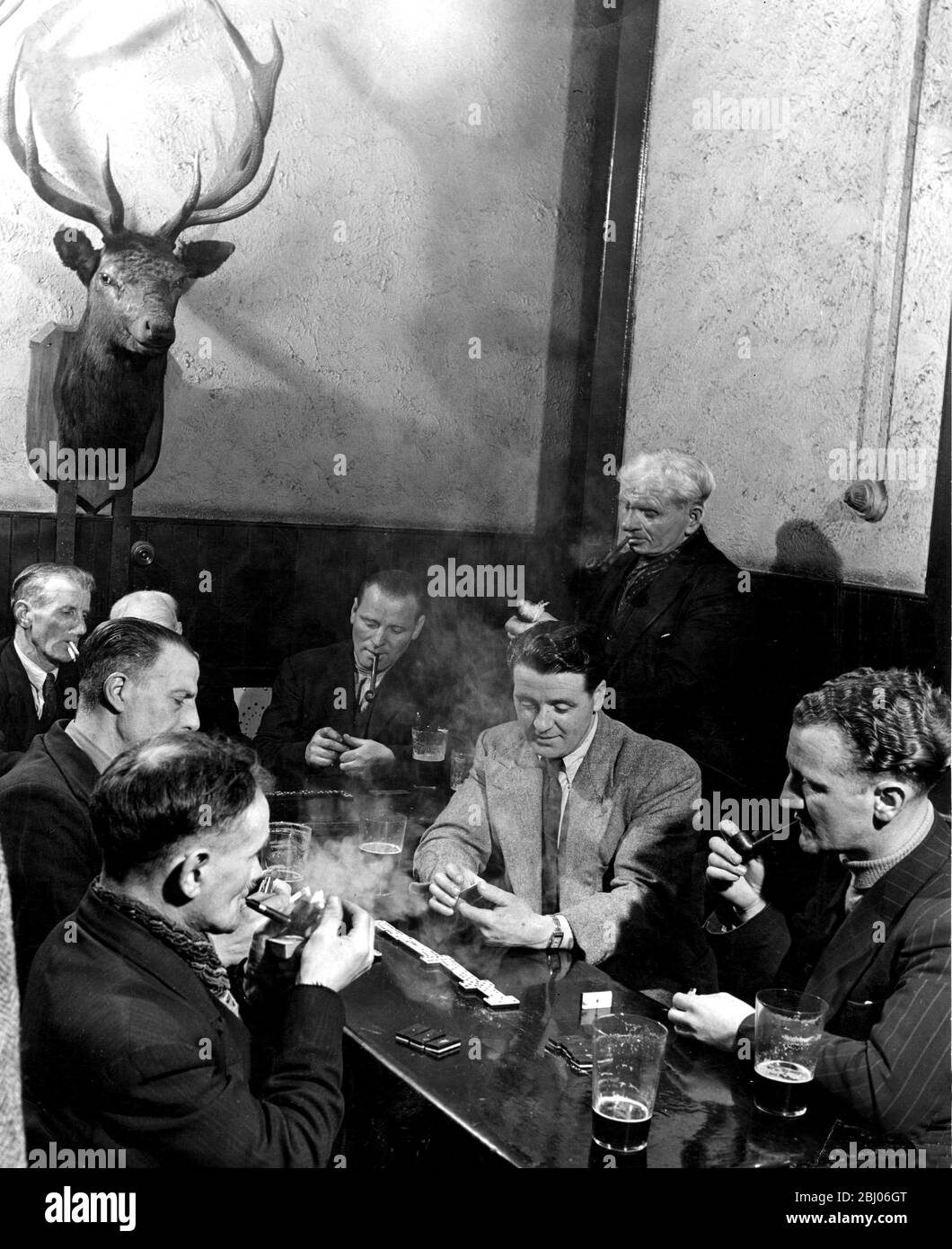 Owen Cairns, ein Nietter in den John Brown's Shipyards, Clydebank (zweiter von rechts), spielt Dominosteine im Learag, seinem lokalen Pub. - 9. Mai 1950 Stockfoto