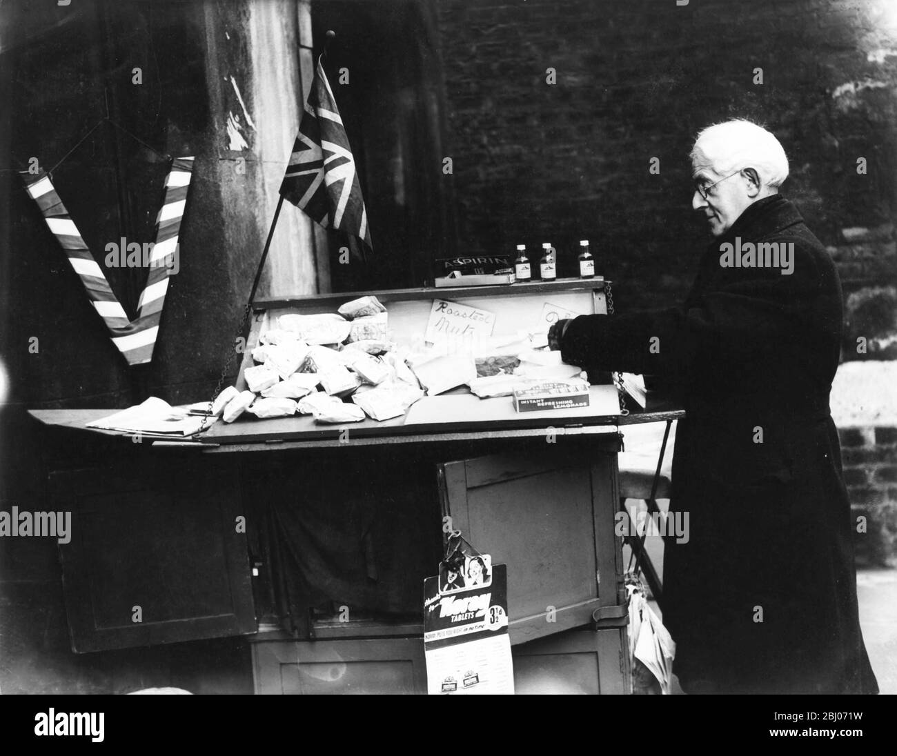 Herr Daivd Healy , 63 Jahre alt, war seit 22 Jahren an seinem Stand vor dem Old Tudor Gate in Lincoln's Inn, London. Der Stand wird seit mehr als 75 Jahren von seiner Familie geführt. Herr Healy übernahm den Stand von seiner Mutter, als er nach dem letzten Krieg demobilisiert wurde. Er diente auch in der Armee während der Burenkrieg. In den Vorkriegszeiten war der Stand mit Schokolade und Süßigkeiten aller Art geladen, aber in der Kriegszeit London sind die einzigen Dinge zum Verkauf Erdnüsse. - 1941 - Planet News - Stockfoto