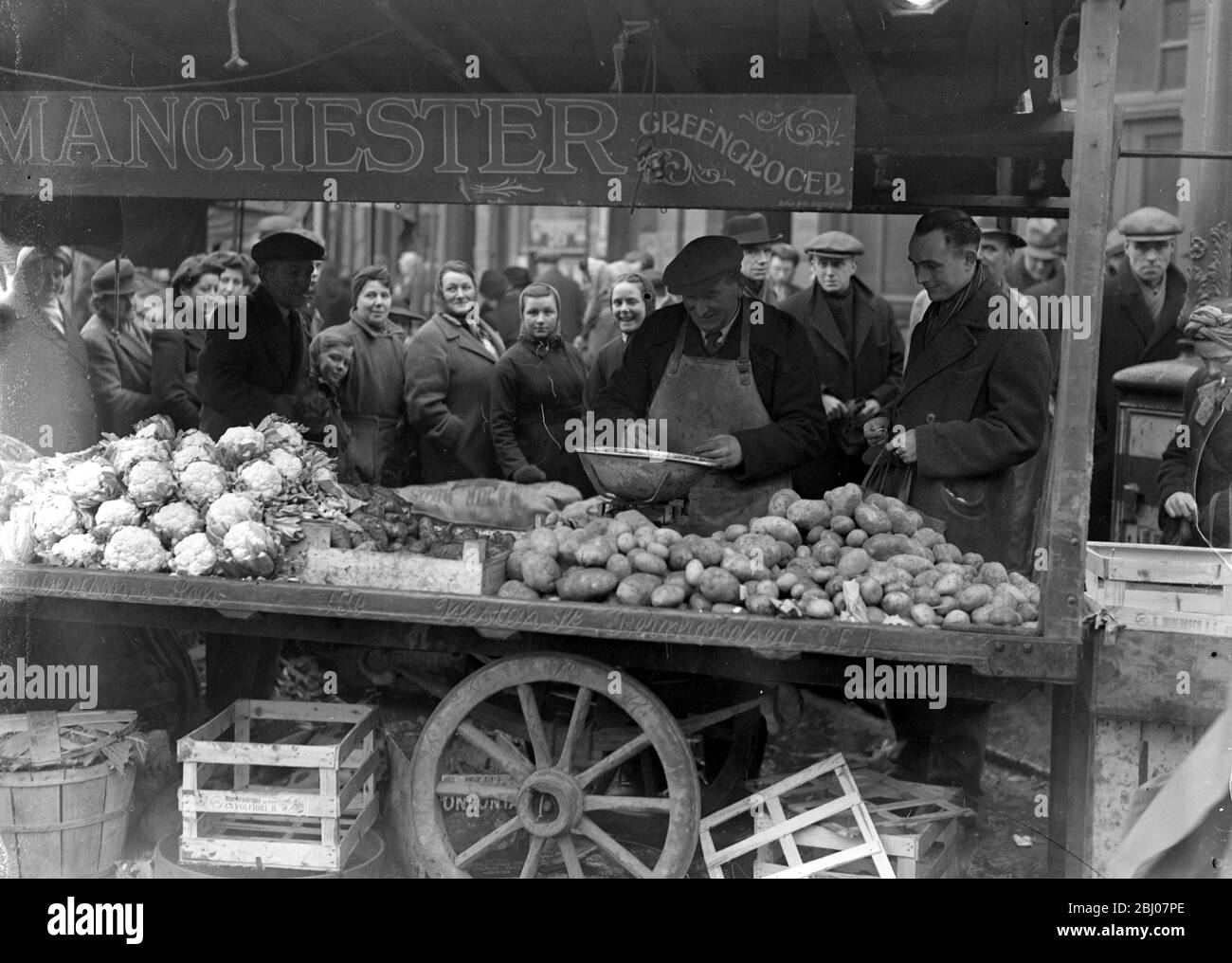 Das Wetter bringt einen Mangel an Kartoffeln . Die Versorgung mit Potatoten wurde durch das Wetter ernsthaft bedroht, da die Bauern nicht in der Lage waren, die Schellen zu öffnen. Eine Schlange für Kartoffeln am beliebten Sam Manchester 's Stand gesehen am Beresford Square, Woolwich - 8. März 1947 Stockfoto