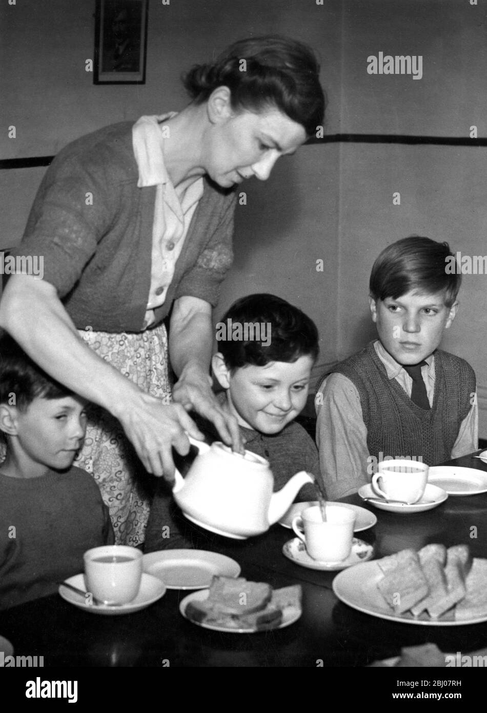 Mutter, die ihren Kindern in den 1950er Jahren Tee serviert Stockfoto
