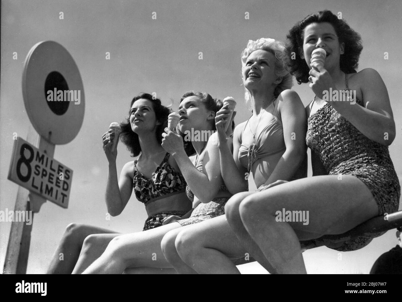 Vier junge Frauen genießen die Sonne auf den Schienen auf Bournemouth Meer vor, während sie Eis essen. - 24. Mai 1947 Stockfoto