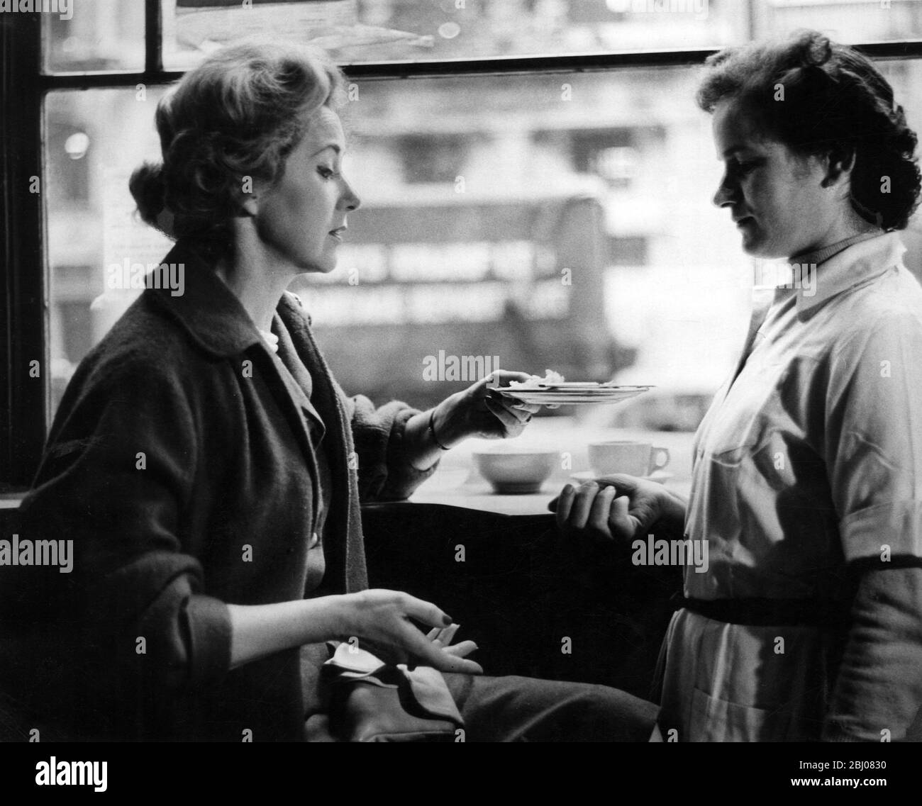 Frau reicht einer Kellnerin in einem Café in London, England, einen leeren Teller - 26. März 1960 - Stockfoto
