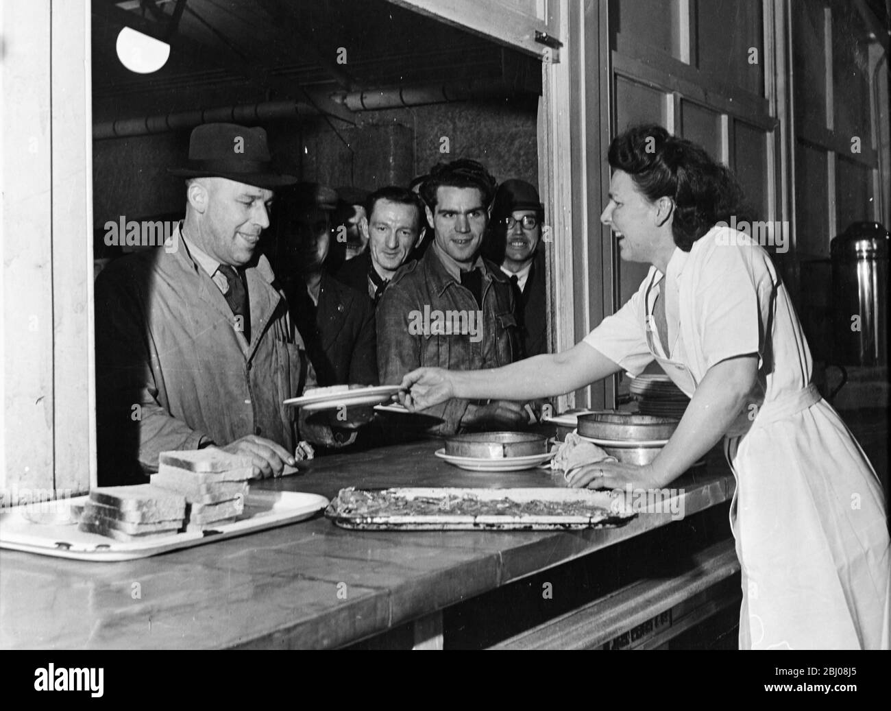 Die Kantine der Austin Motor Works, wo die Arbeiter Schlange stehen, um bedient zu werden. - Longbridge, Birmingham, England - 1947 - Stockfoto