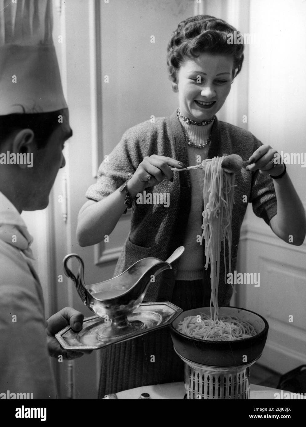 Frau Wanda Jennings, die Rom besucht, versucht, unter den wachsamen Augen des Küchenchefs im Hotel ein Gericht mit italienischen Spaghetti zuzubereiten. - 12. November 1954 Stockfoto