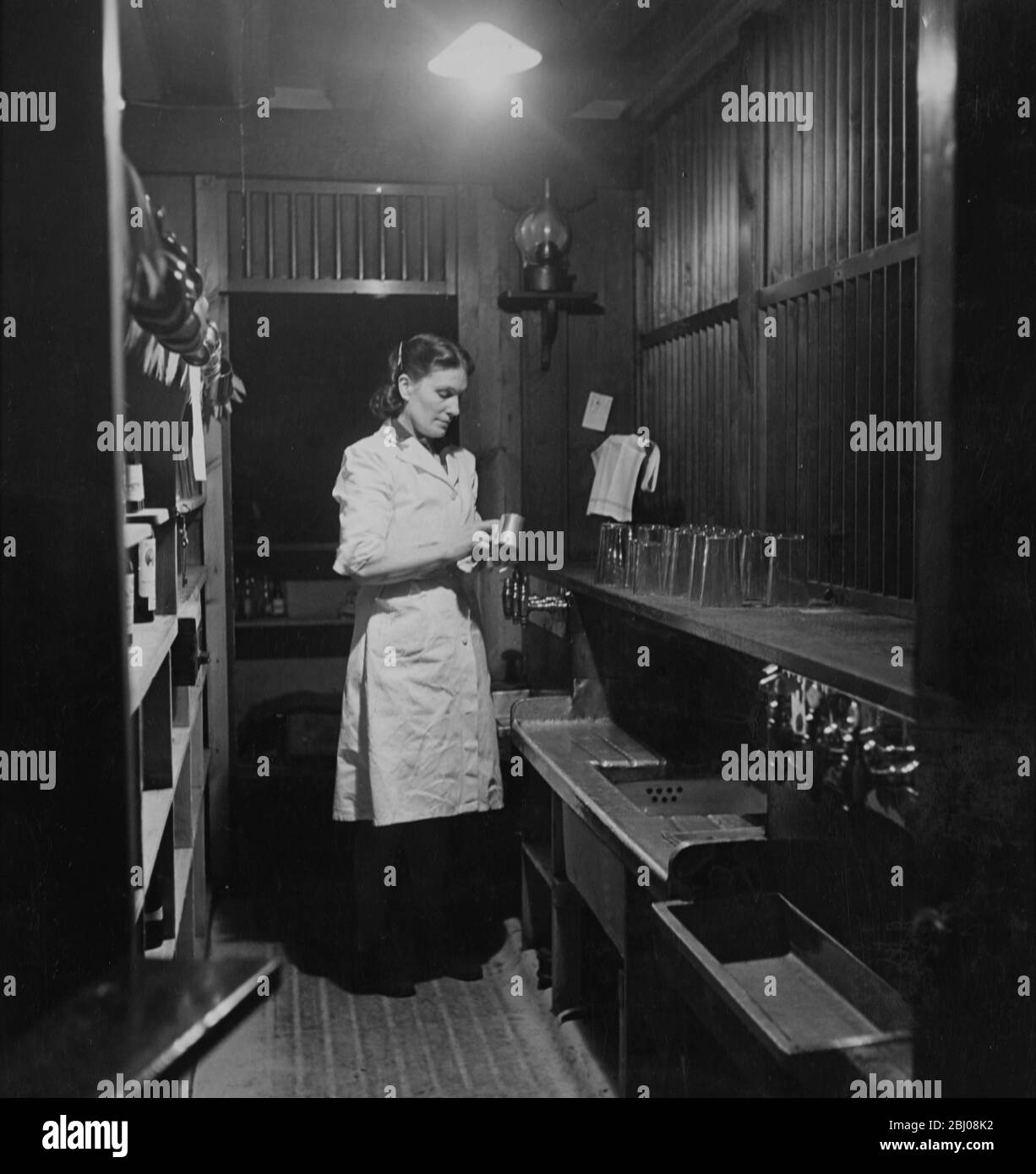 Eine Barkeeper putzt einen Biertankard in der Globe Tavern. Ein Pub im Staatsbesitz in Longtown, Carlisle, Cumbria, England. - Dezember 1948 Stockfoto