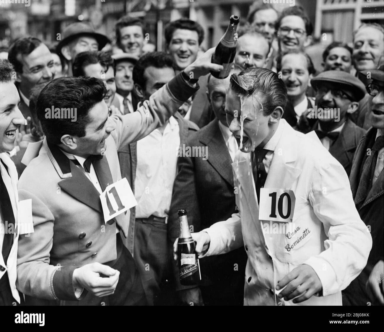 Michael Bushell, der jüngste Konkurrent mit 15 Jahren, wird von Platz zwei Guido adorne mit Champagner bespritzt, nachdem er das Soho Fair Wazers' Race vom Soho Square zur Greek Street gewonnen hatte, während er ein Tablett mit einer halben Flasche Wein, einem Glas und einer Aschenschale trug. Soho, London, England. - 13. Juli 1958 Stockfoto