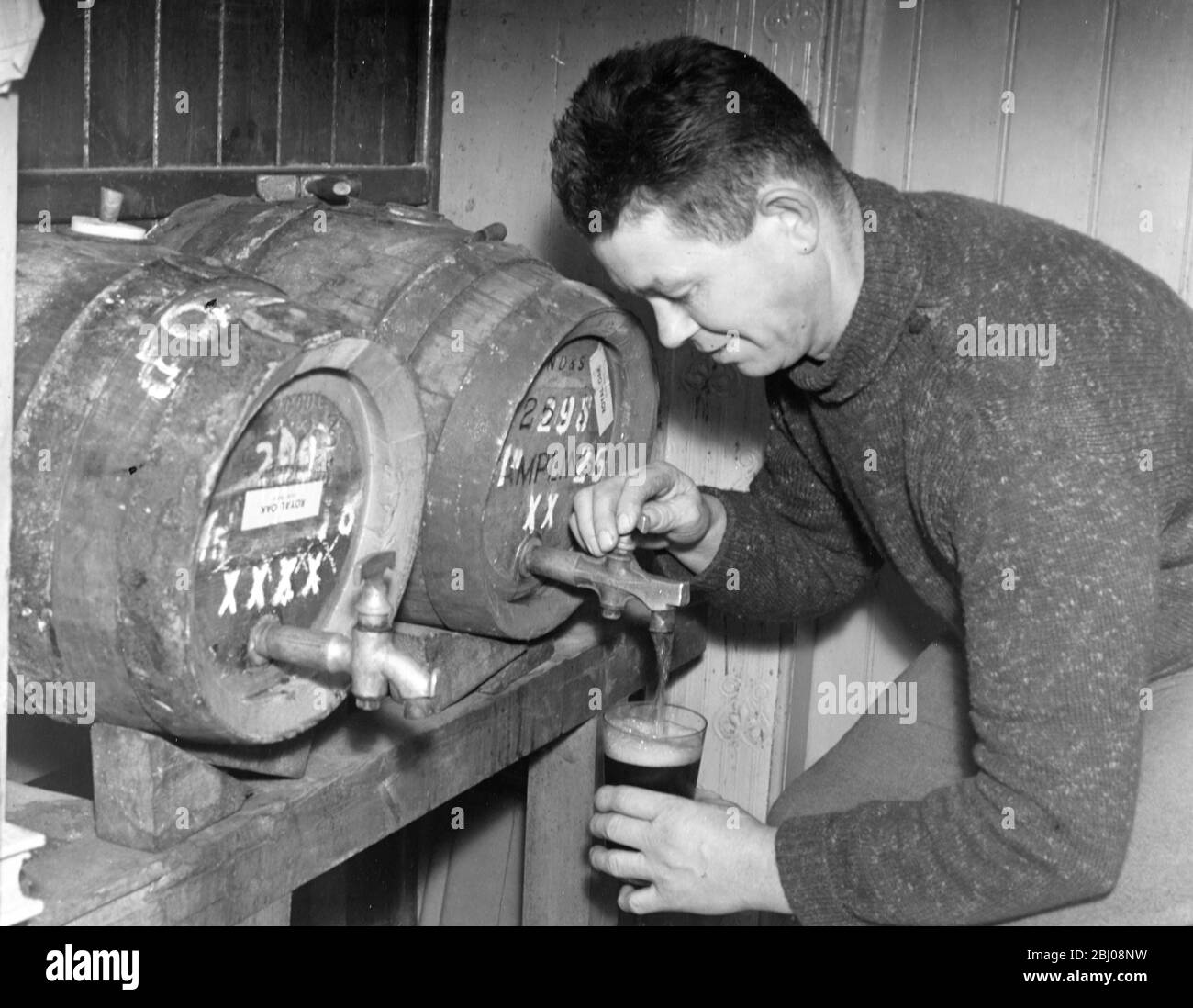 Der Vermieter gießt ein Bier im Royal Oak Inn, High Hurstwood bei Uckfield, Sussex, England. - Dezember 1947 Stockfoto