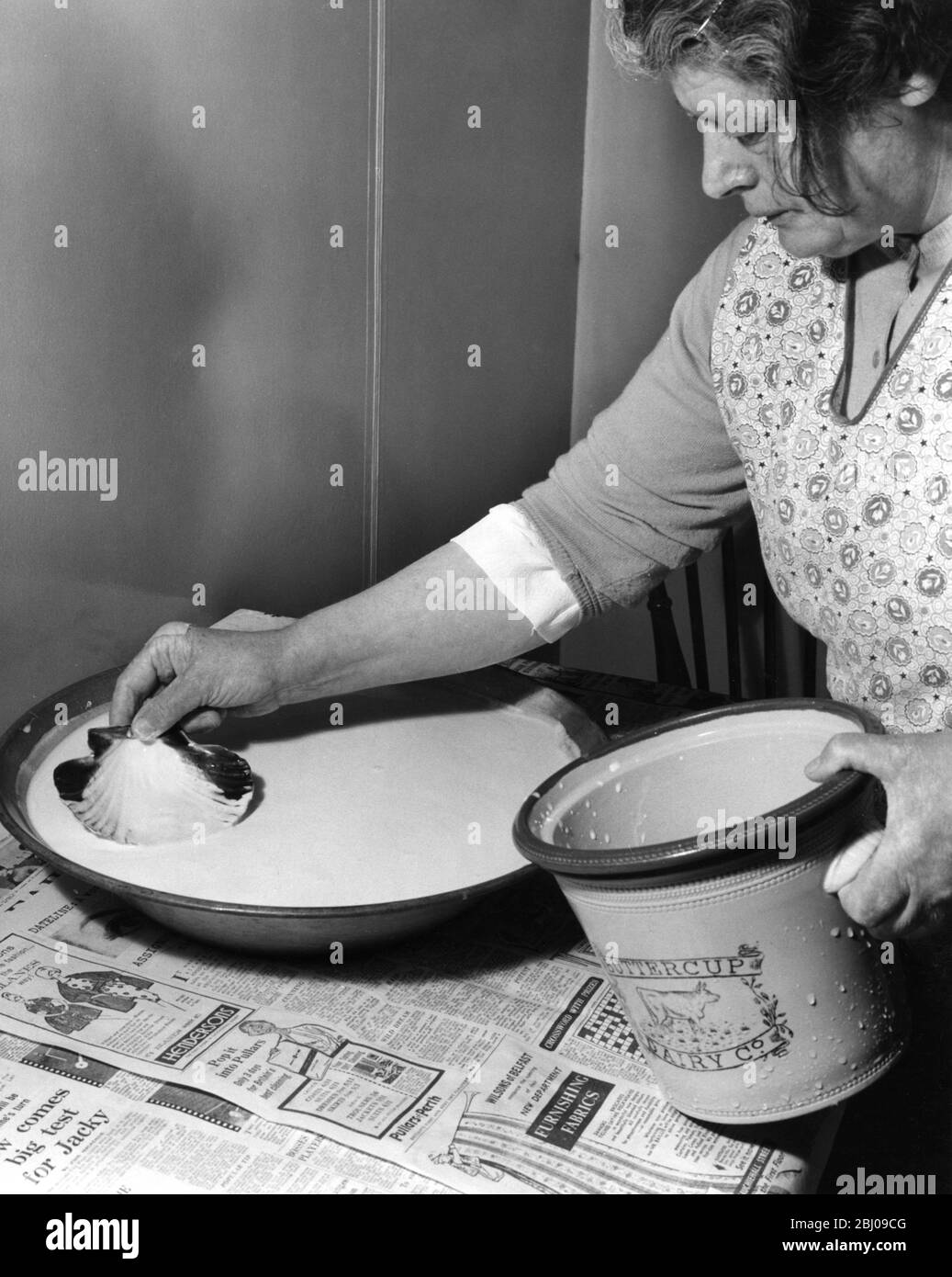 Miss Peggy Macleod Butter machen - Abziehen der Creme aus thee Cremepfannen Beachten Sie, dass sie Skollop Sheel in Daliburgh South Uist Äußere Hebridgen Schottland verwendet - September 1961 Stockfoto