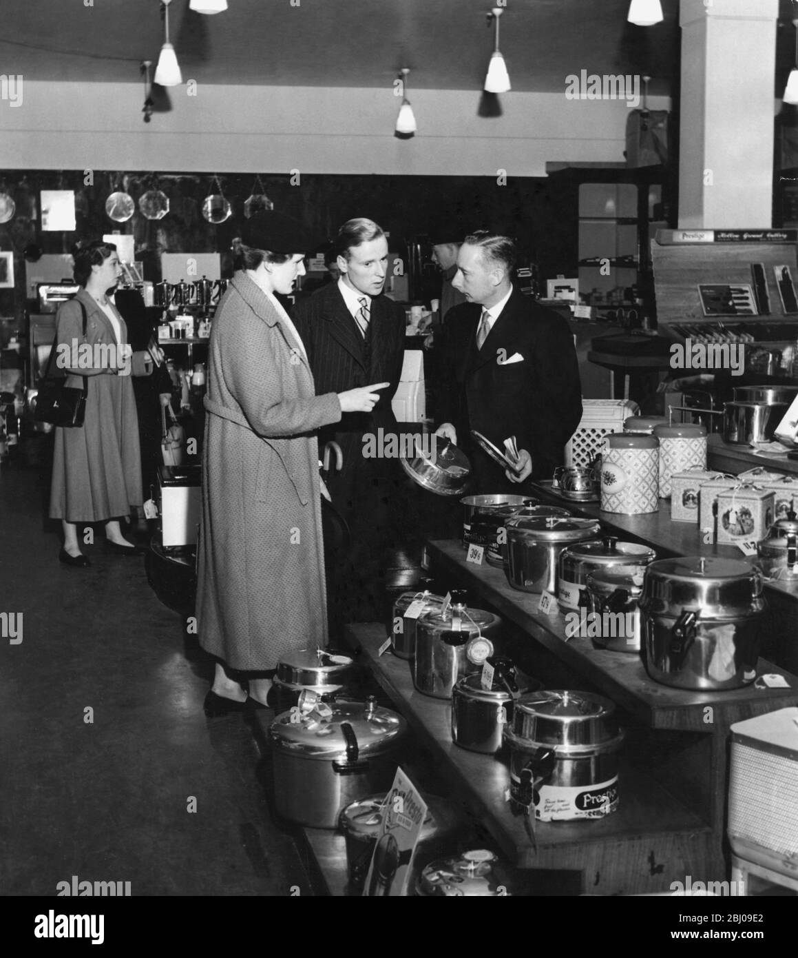 Ein engagiertes Paar in einem Küchenbeschlag, das einen Schnellkochtopf kaufen möchte. 1952. Stockfoto