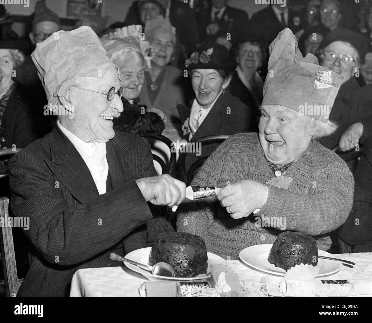 Ellen Clarke, 86, zieht einen Weihnachtskracker mit Henry Stutsbury, 88, als die beiden ältesten Mitglieder von Laindon Darby und Joan Club. Während der jährlichen Weihnachtsfeier in der Memorial Hall, Laindon, Essex, England. - 12. Dezember 1959 Stockfoto