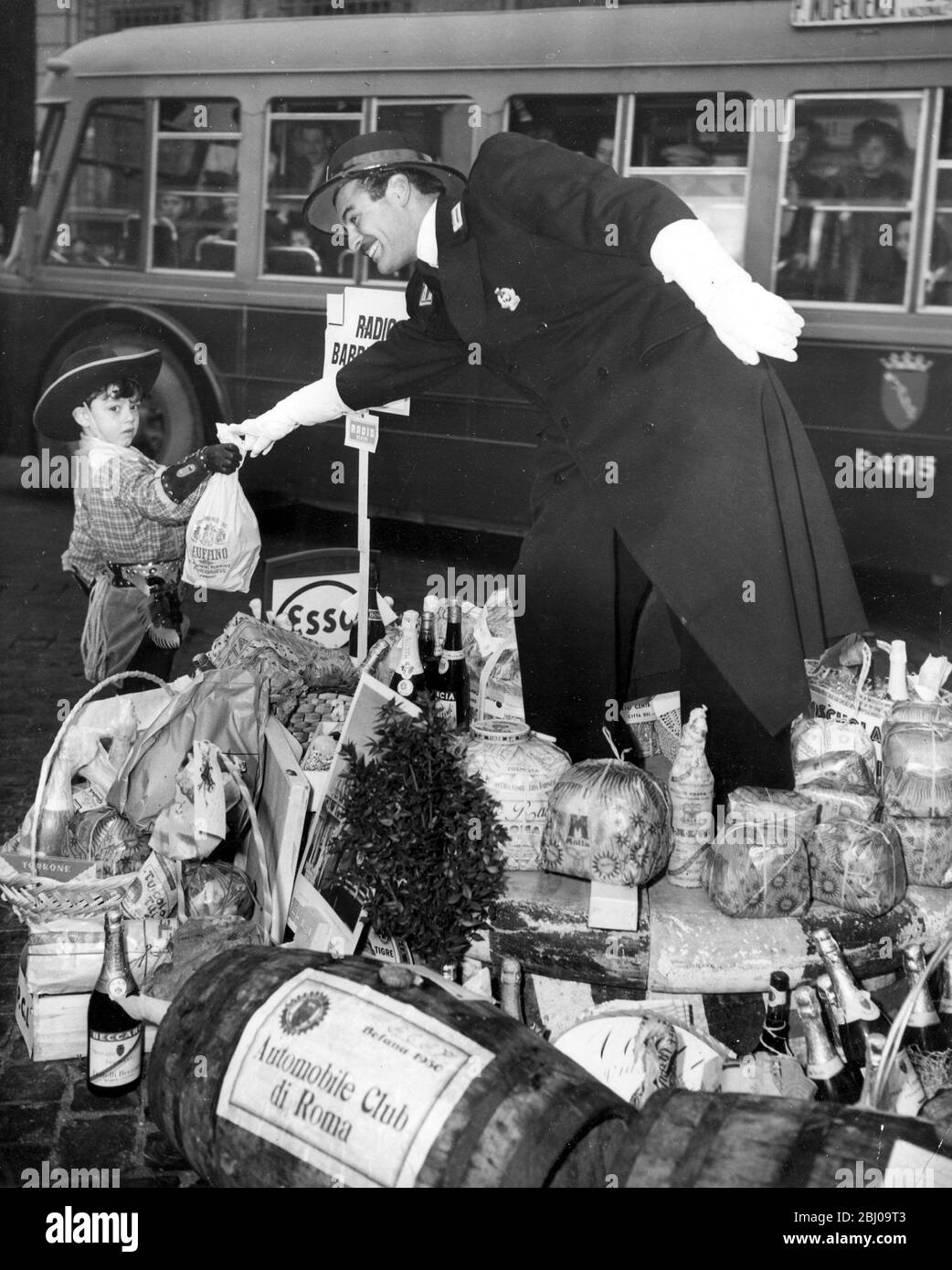 Italien . - 6. Januar Fest der Epiphanie in Rom . - der vierjährige Junge in Cowboy-Outfit reicht der Verkehrspolizei auf der Piazza Venezia eine Flasche Wein. - 9. Januar 1950 - - Stockfoto