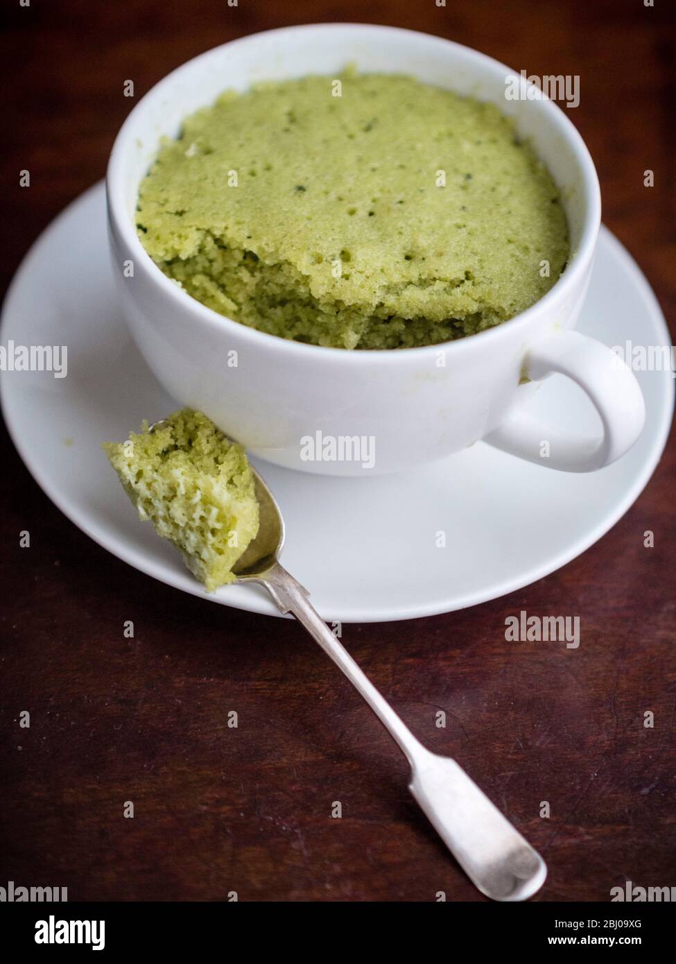 Köstliche einfache Kuchen mit gemahlenen Mandeln und Matcha Grüntee-Pulver, in einer Tasse in einer Mikrowelle gebacken. Stockfoto