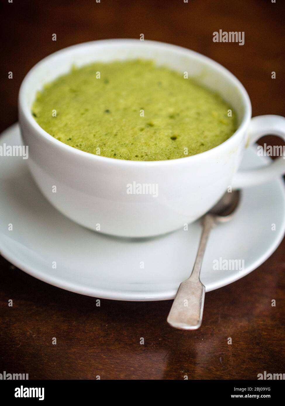 Köstliche einfache Kuchen mit gemahlenen Mandeln und Matcha Grüntee-Pulver, in einer Tasse in einer Mikrowelle gebacken. Stockfoto