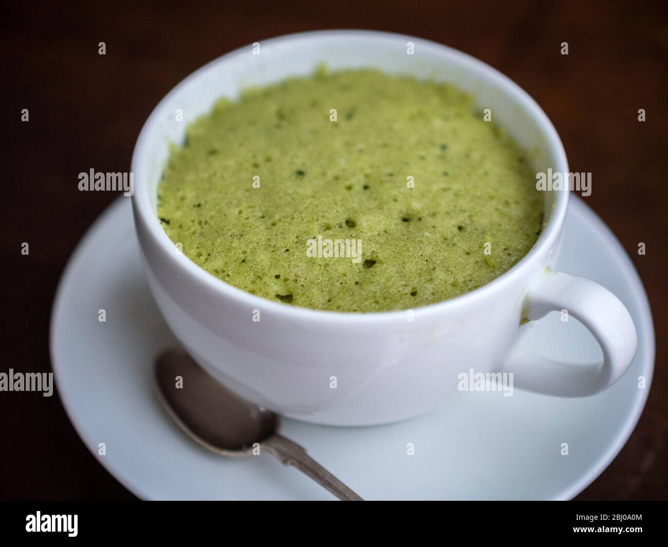 Köstliche einfache Kuchen mit gemahlenen Mandeln und Matcha Grüntee-Pulver, in einer Tasse in einer Mikrowelle gebacken. Stockfoto