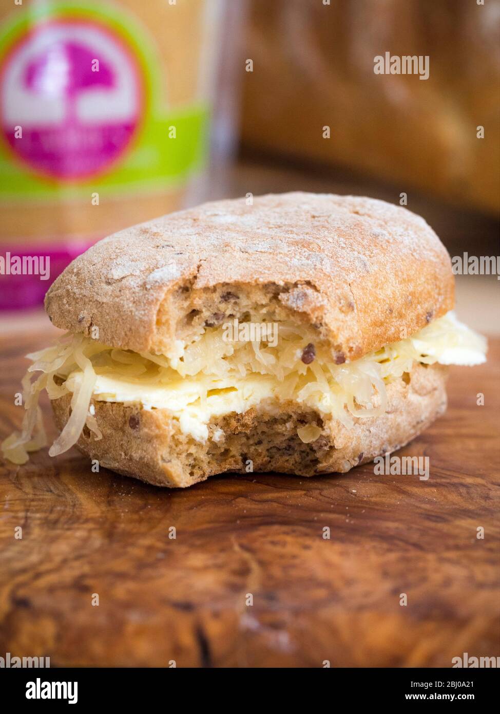 Nährendes Sandwich zum Mittagessen aus dünn geschnittenem Cheshire-Käse mit Sauerkraut auf braunem Ciabatta. (Glutenfreies Brot) Stockfoto