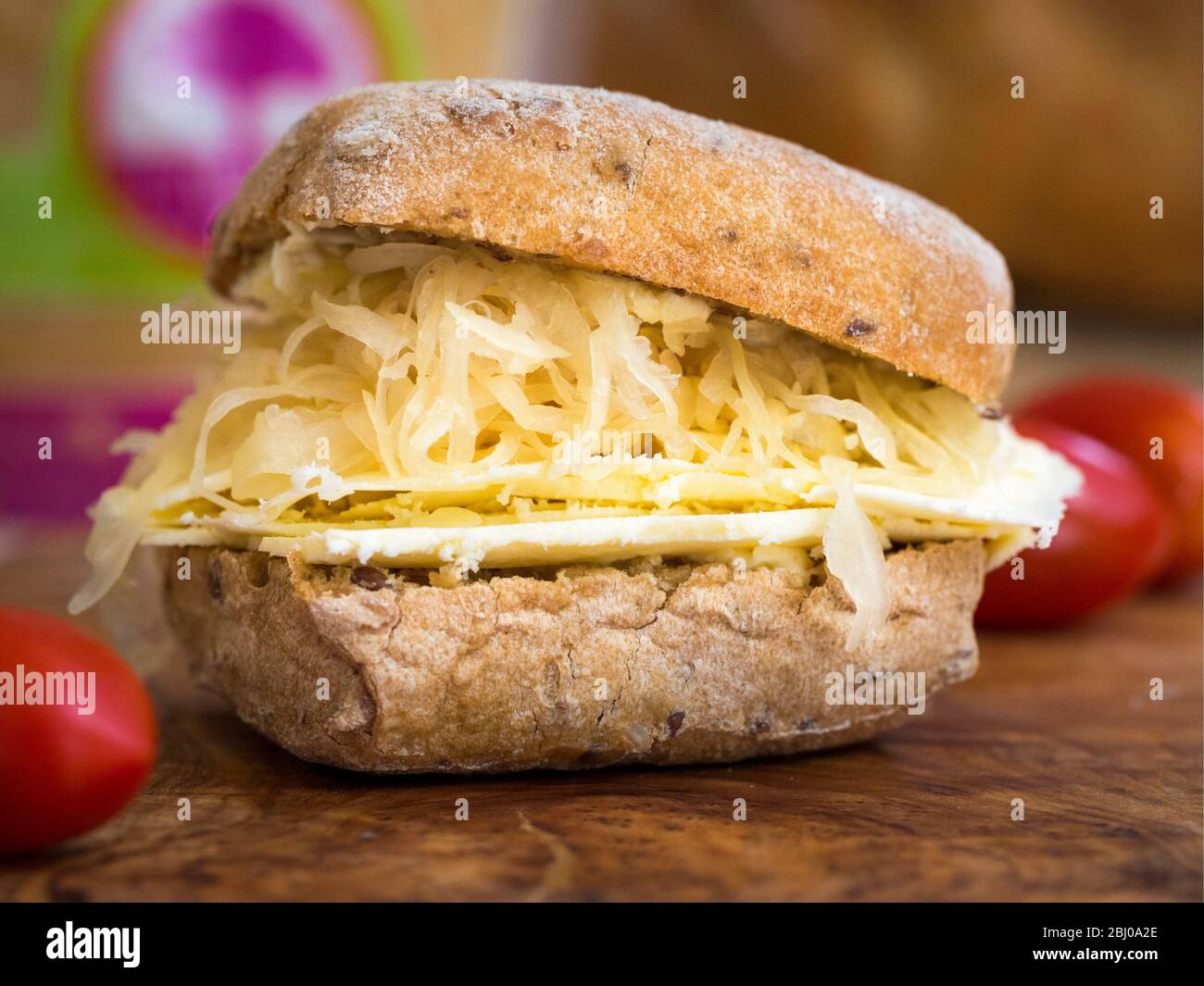 Nährendes Sandwich zum Mittagessen aus dünn geschnittenem Cheshire-Käse mit Sauerkraut auf braunem Ciabatta. (Glutenfreies Brot) Stockfoto