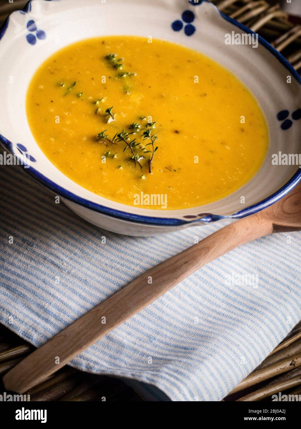 Kürbissuppe mit Knoblauch und Thymian geröstet, serviert in blau-weißen Schüssel mit Holzlöffel Stockfoto