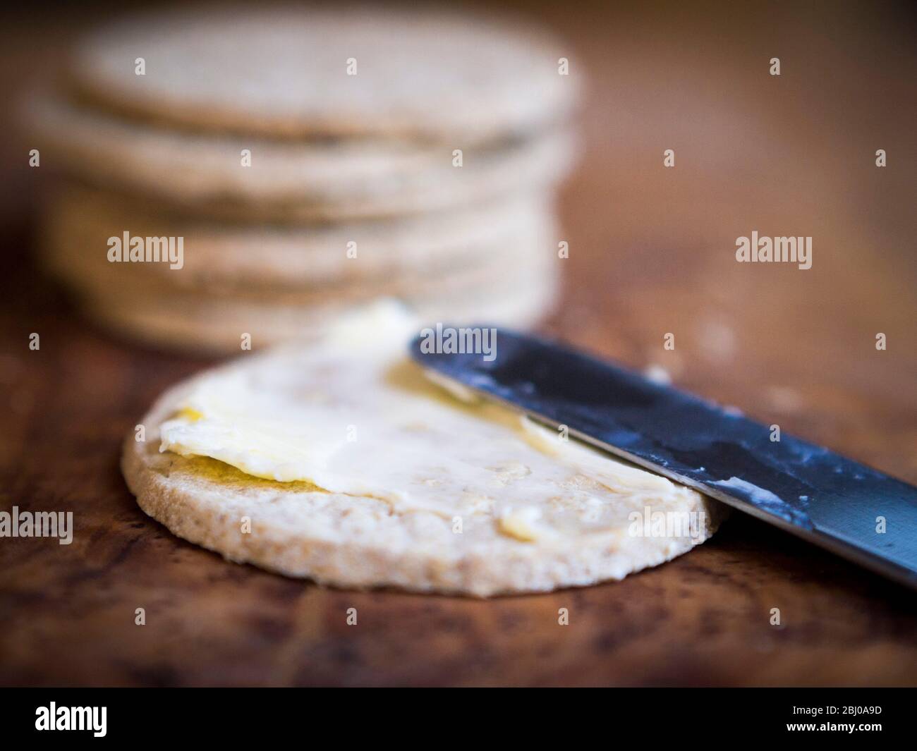 Glutenfreie Nairn's Haferkuchen mit richtiger ungesalzener Butter bestreichen Stockfoto