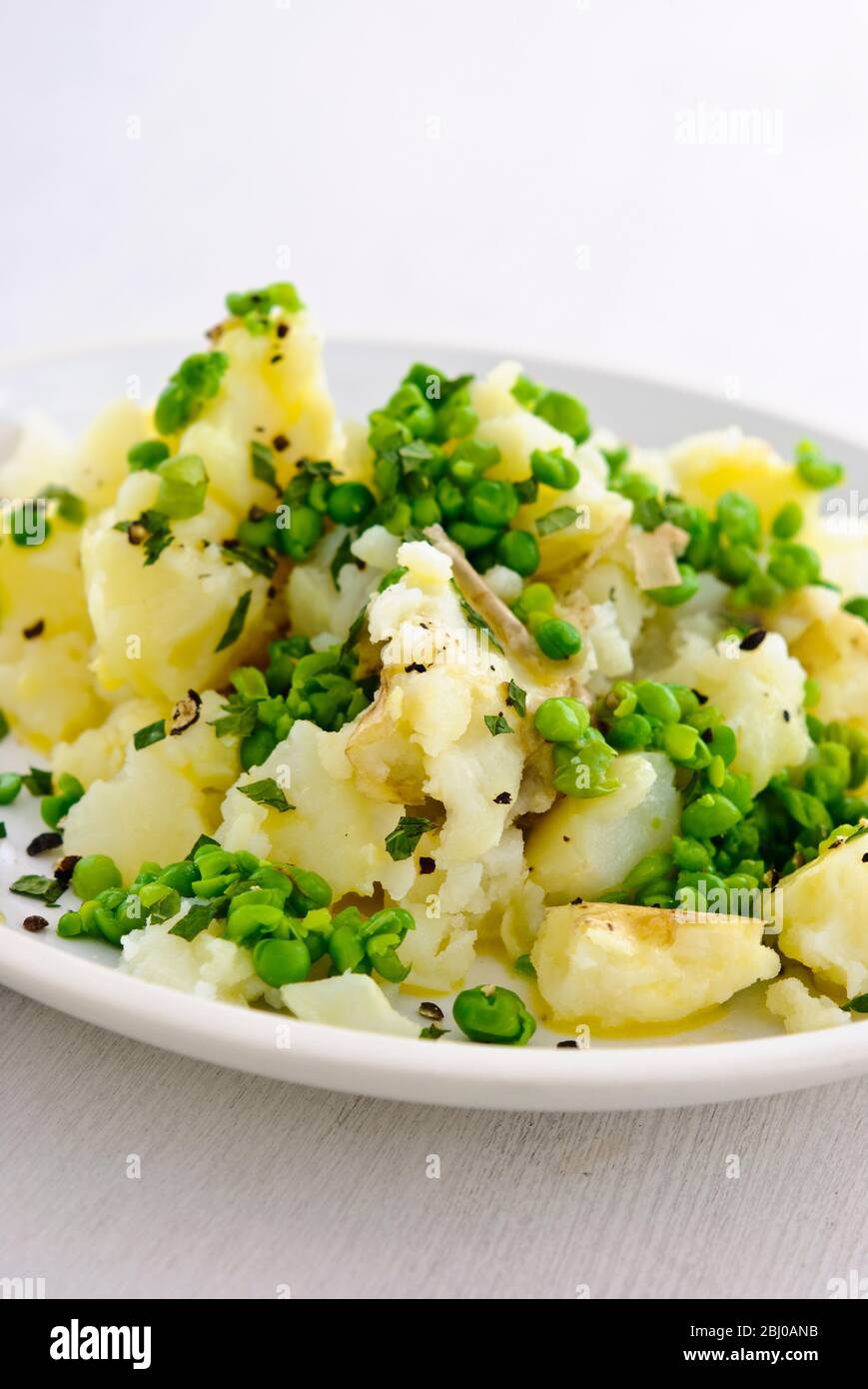 Kartoffel- und Erbsensalat mit Minze und Schnittlauch und grob gemahlenem schwarzem Pfeffer - Stockfoto