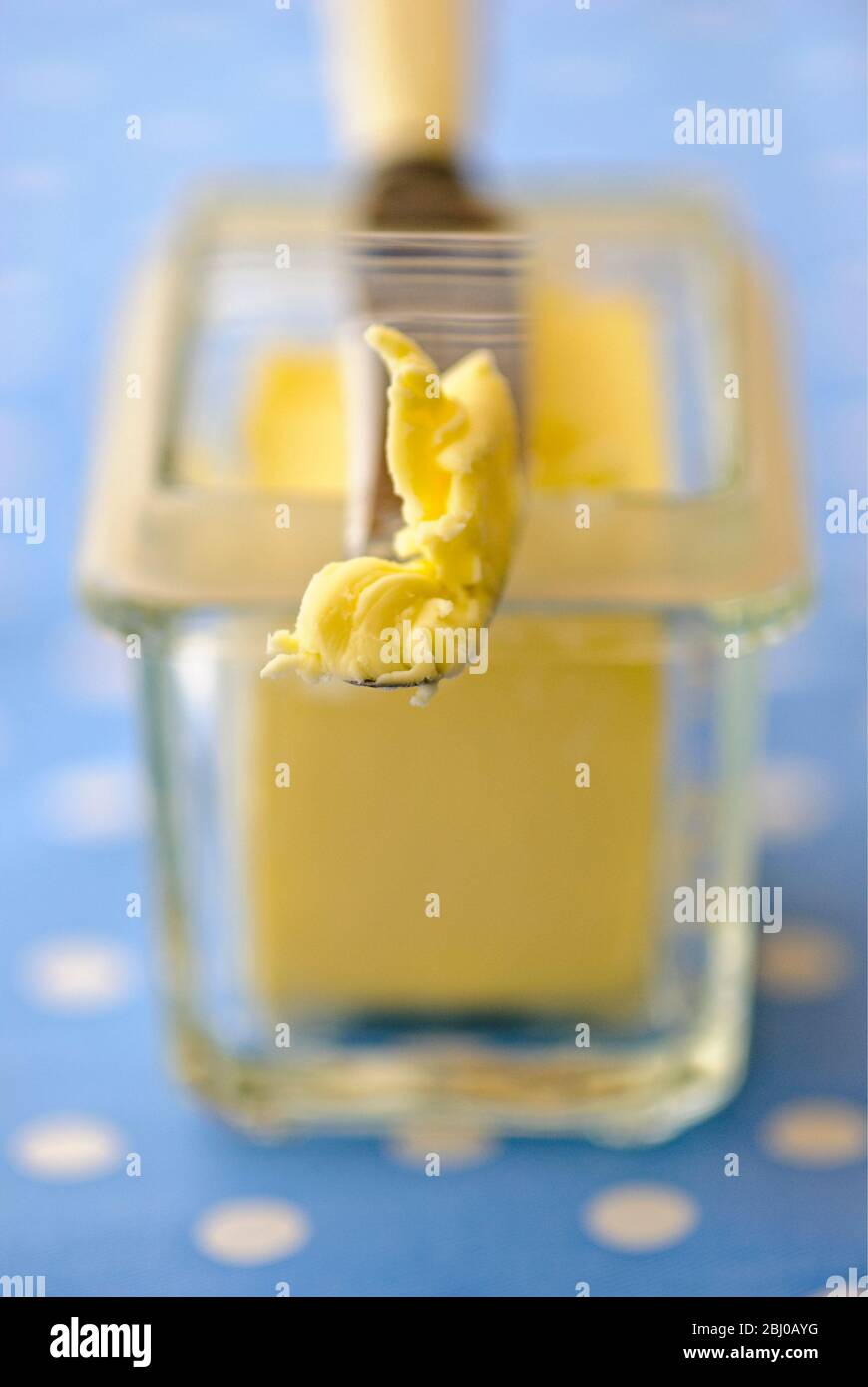 Butterdose aus Glas mit Buttermesser auf blau-weiß gepunkteten Tuch - Stockfoto
