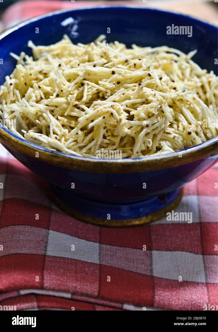 Fein geriebener Sellerie in einer Senf-Vinaigrette in blauer Keramikschale - Stockfoto