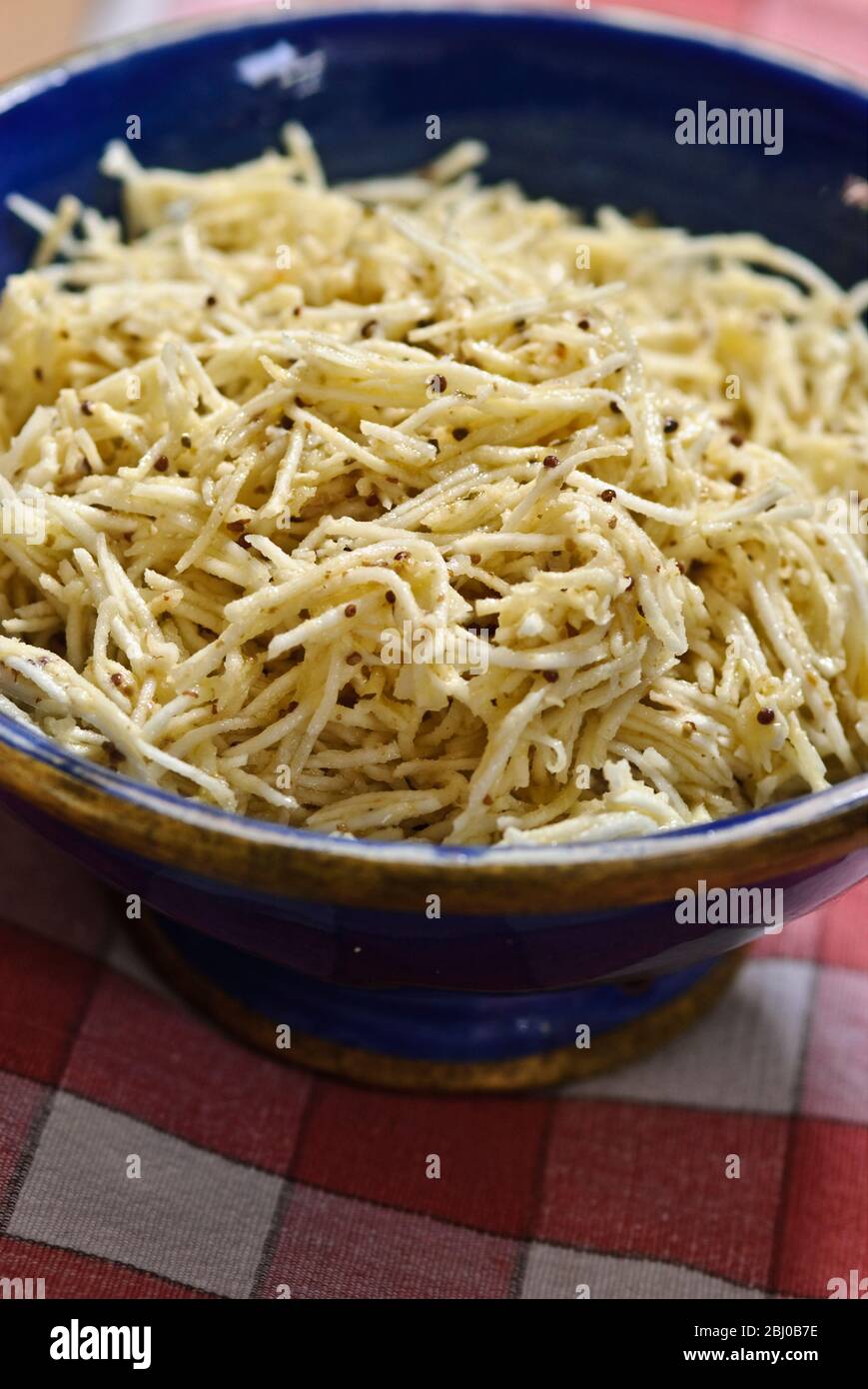 Fein geriebener Sellerie in einer Senf-Vinaigrette in blauer Keramikschale - Stockfoto