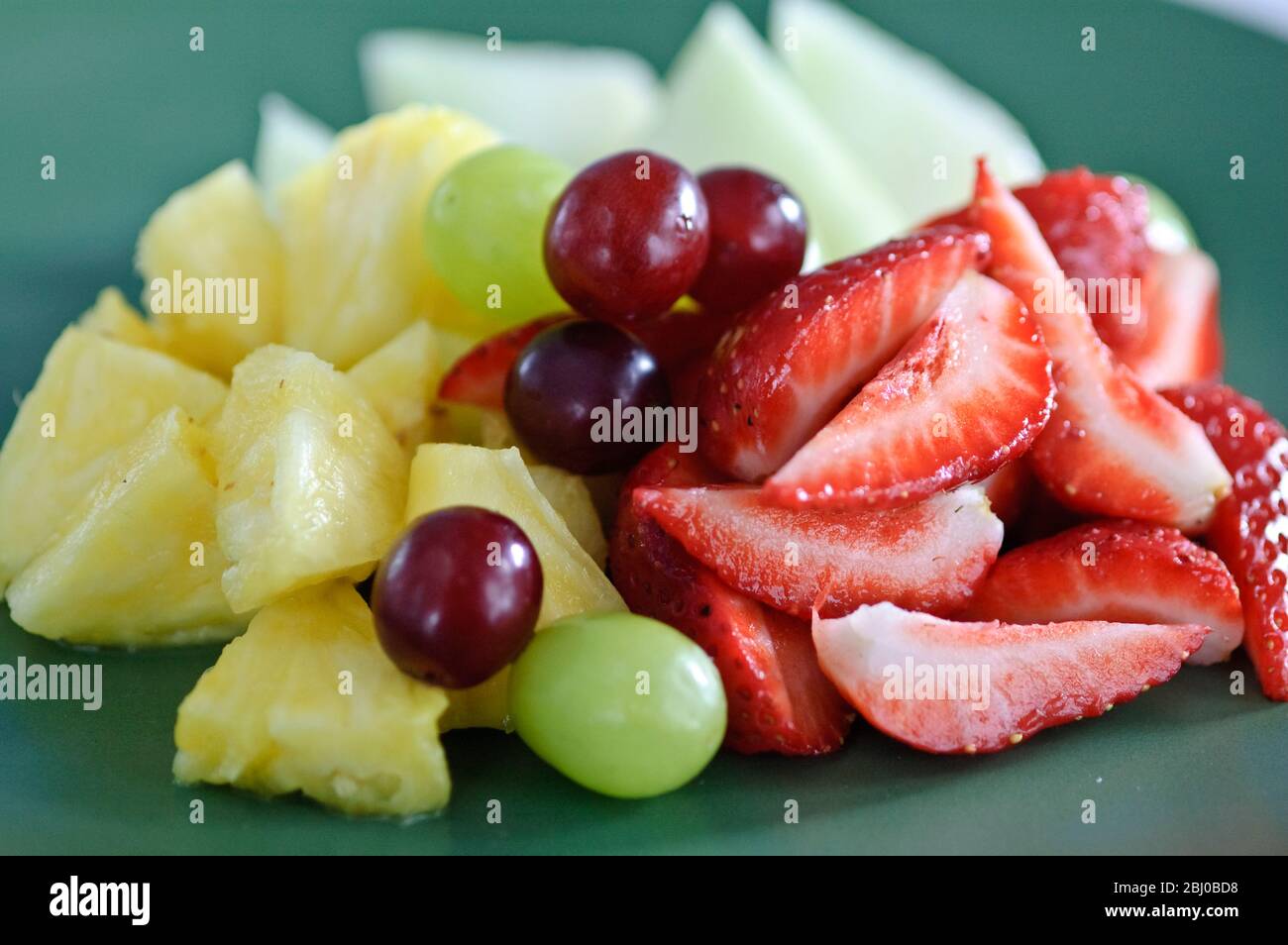 Frischer Obstsalat auf grünem Teller - Stockfoto