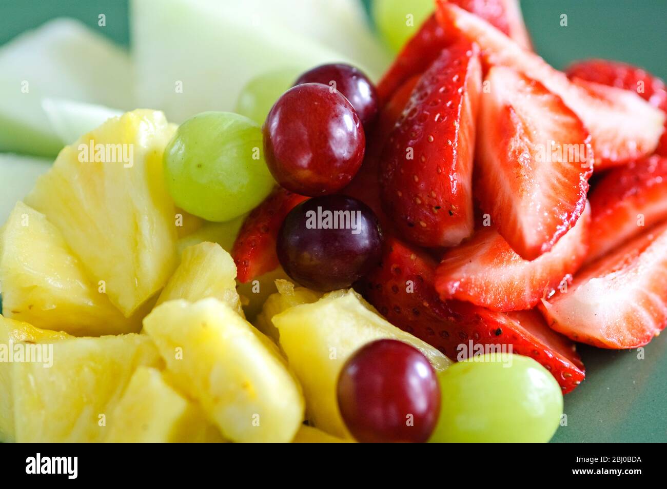 Frischer Obstsalat auf grünem Teller - Stockfoto