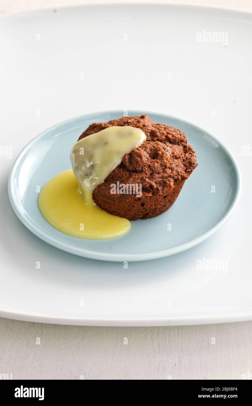 Warme Schokoladenmuffin als Dessert mit Puddingsauce serviert - Stockfoto