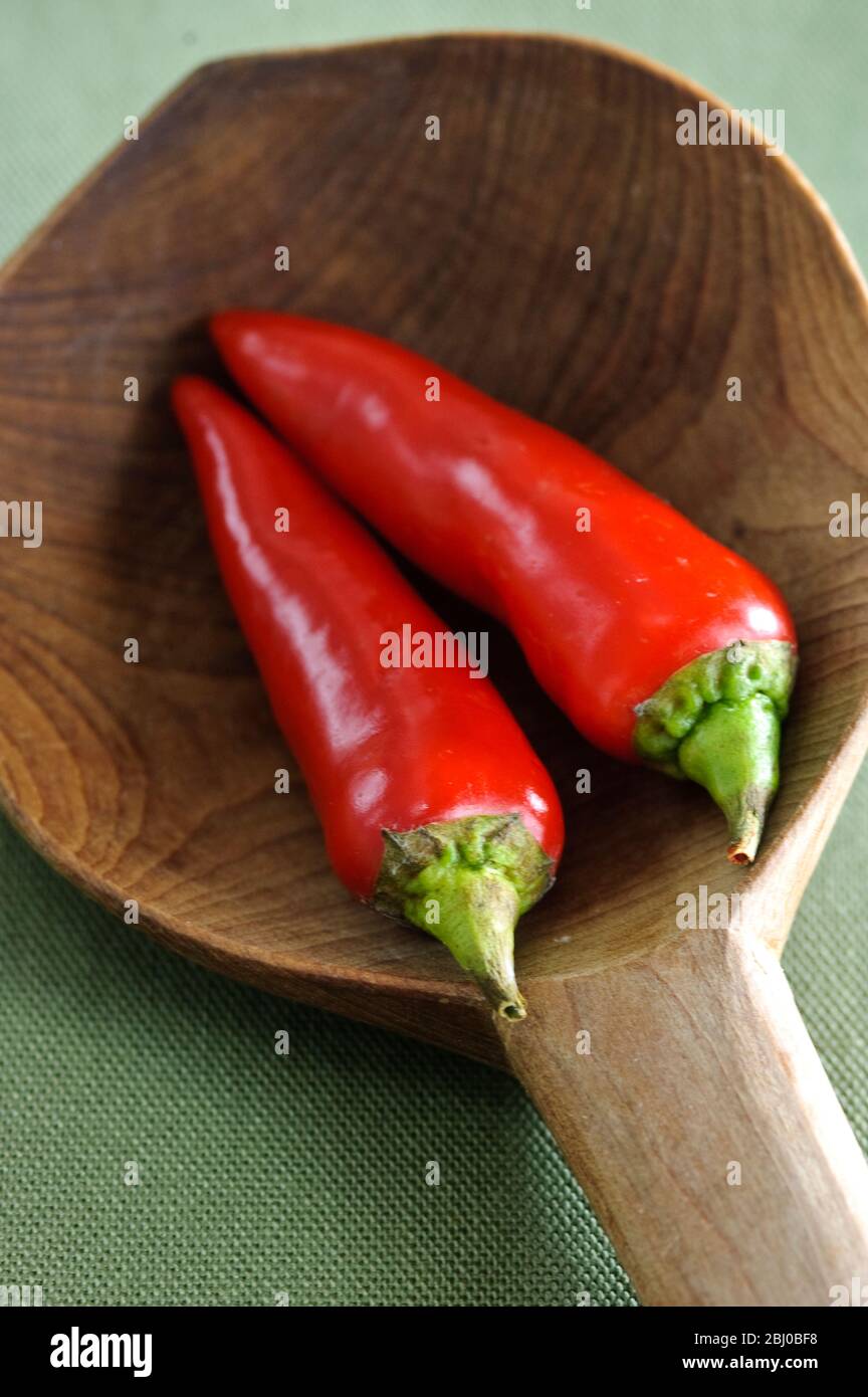 Glänzende rote Chilischoten in großem Holzlöffel - Stockfoto