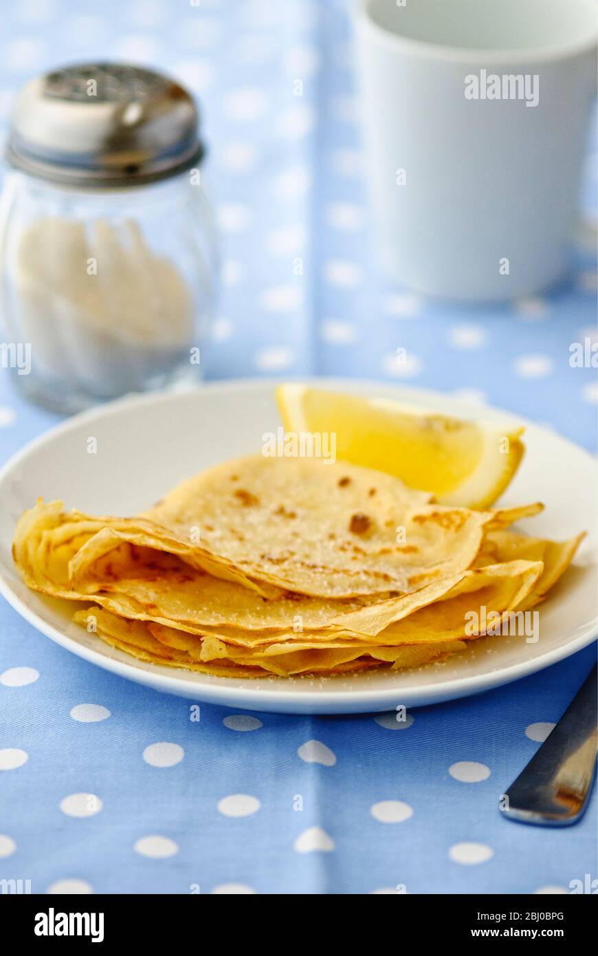 Pfannkuchen in Vierteln gefaltet mit Zucker auf und Zitronenkeil zum Quetschen - Stockfoto