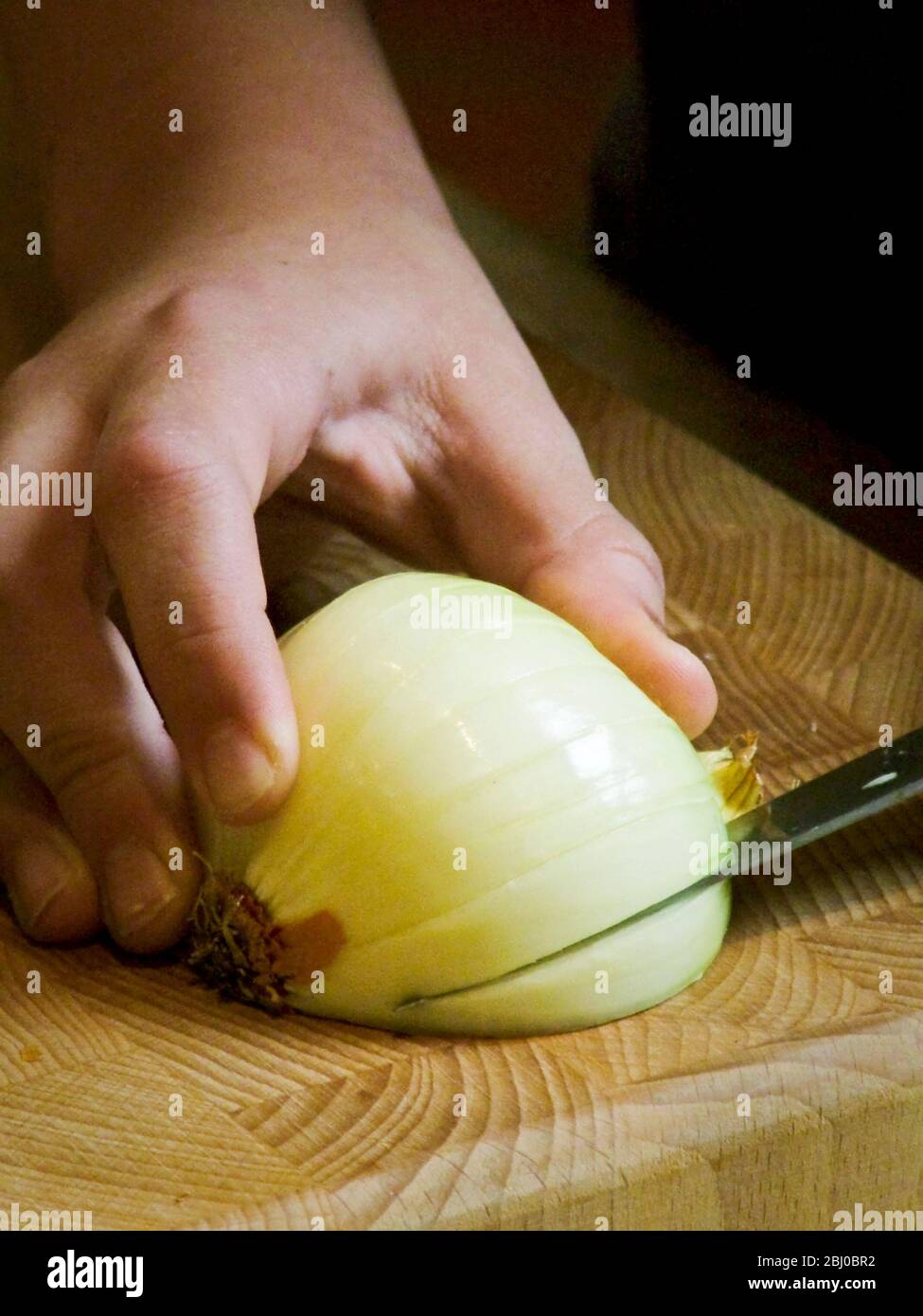 Kind lernen, eine Zwiebel zu hacken - Stockfoto