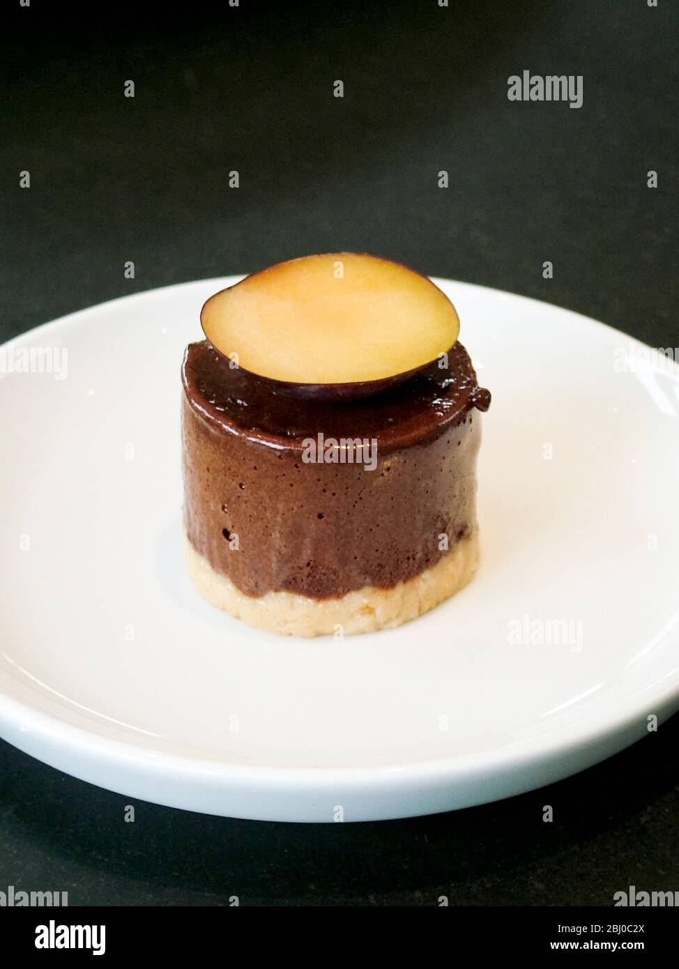 Schokoladenmousse mit Pflaumenscheibe auf weißem Teller - Stockfoto