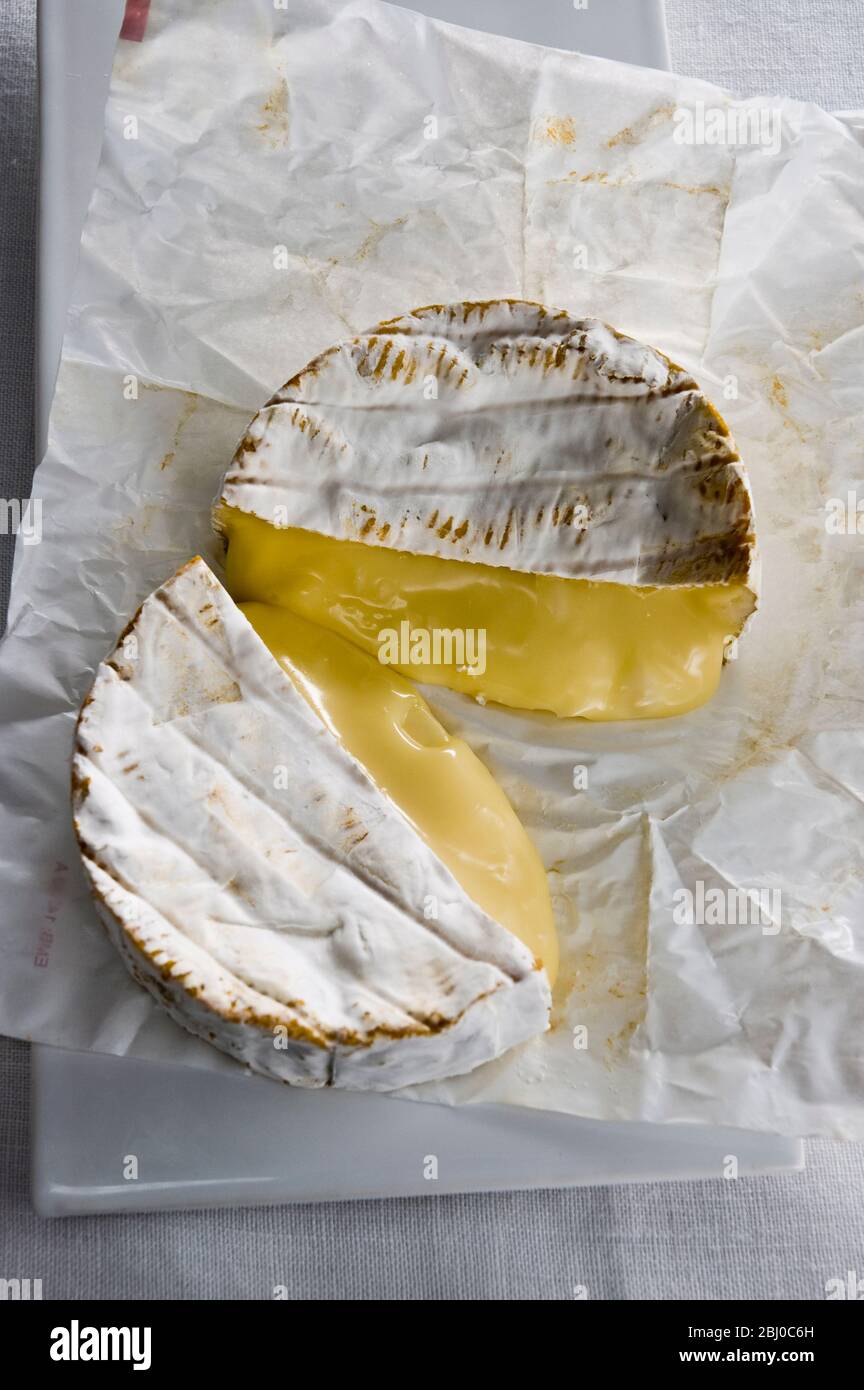 Runder Camembert Käse in zwei Hälften geschnitten mit reifer, laufender Innenausstattung - Stockfoto