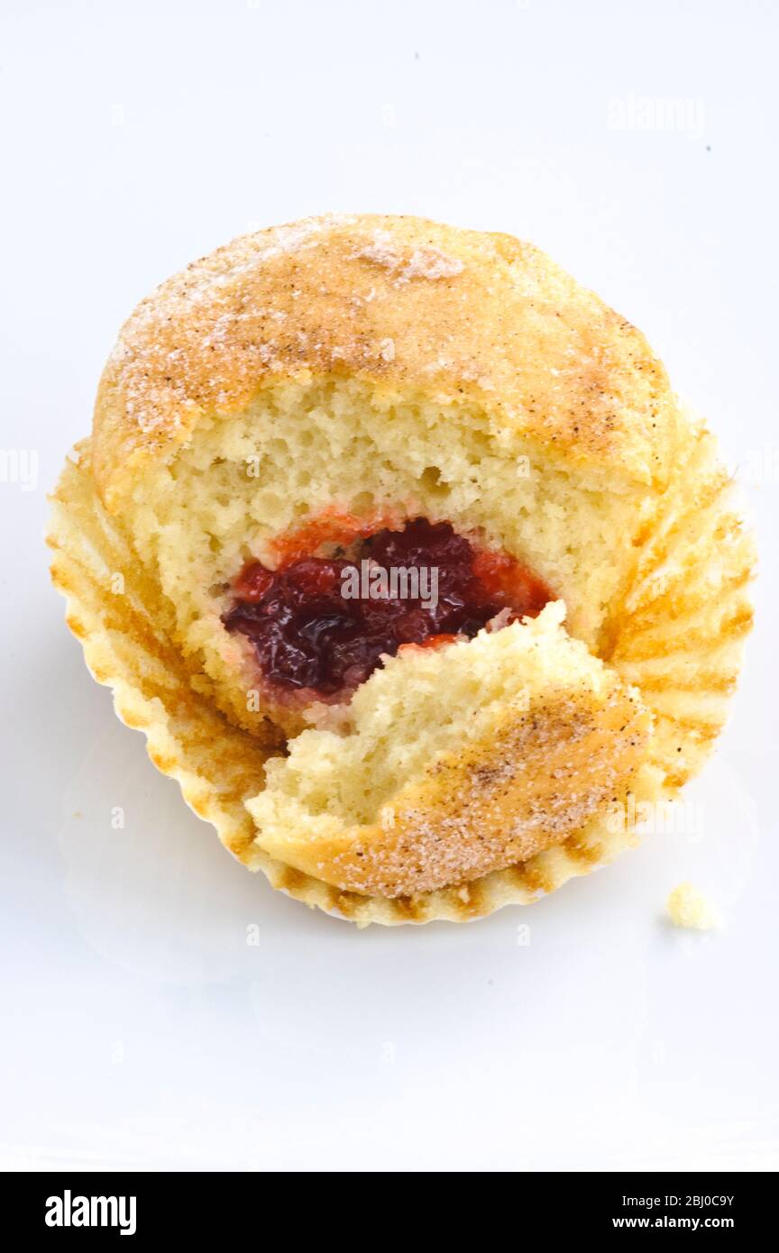Muffin mit zuckerhaltiger Spitze, gefüllt mit Marmelade (Gelee), aufgebrochen, um die Füllung anzuzeigen. Ein Muffin maskiert als Donut! - Stockfoto