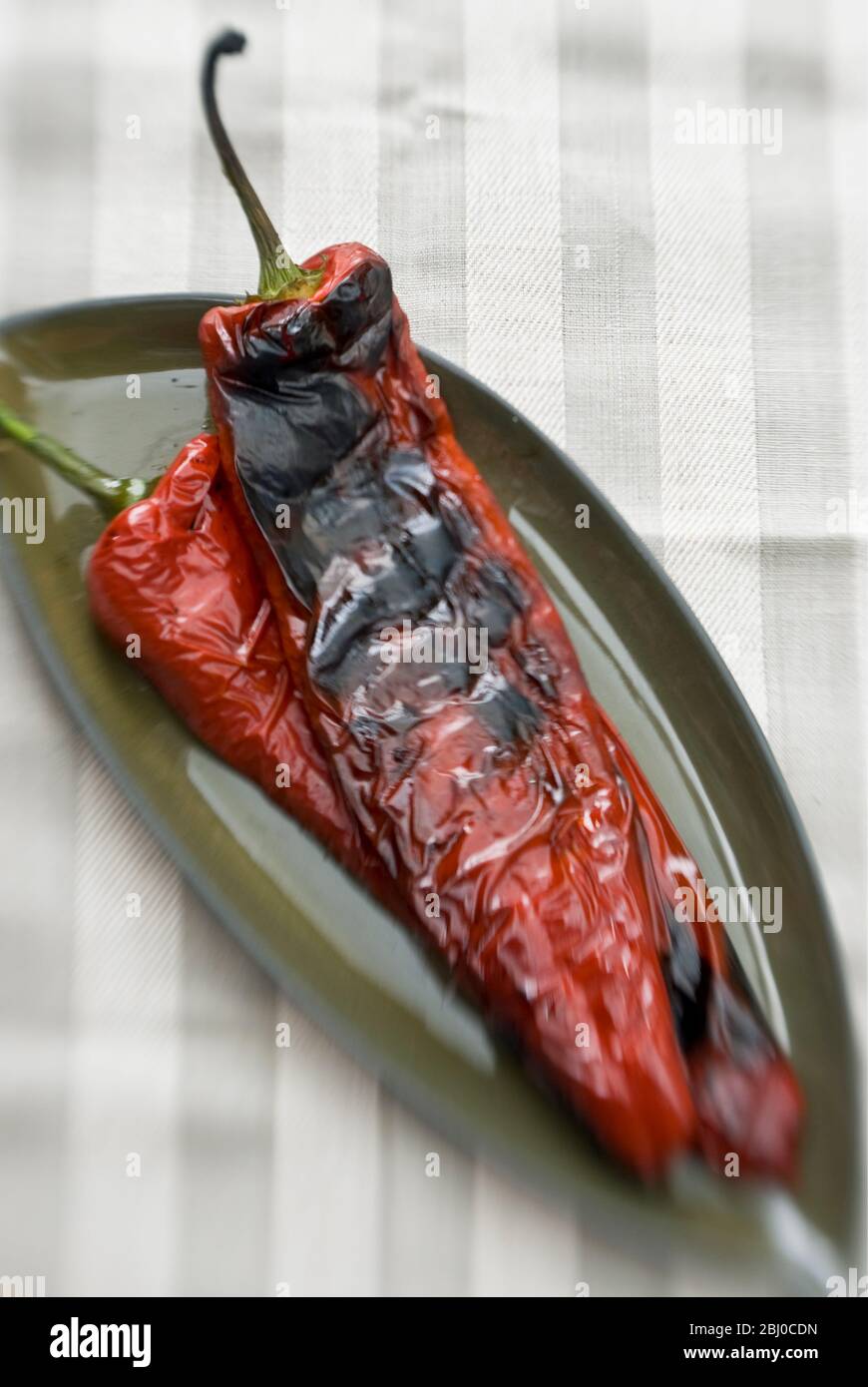 Lange rote Paprika auf dem Grill gegrillt zeigt Blasen Haut - Stockfoto