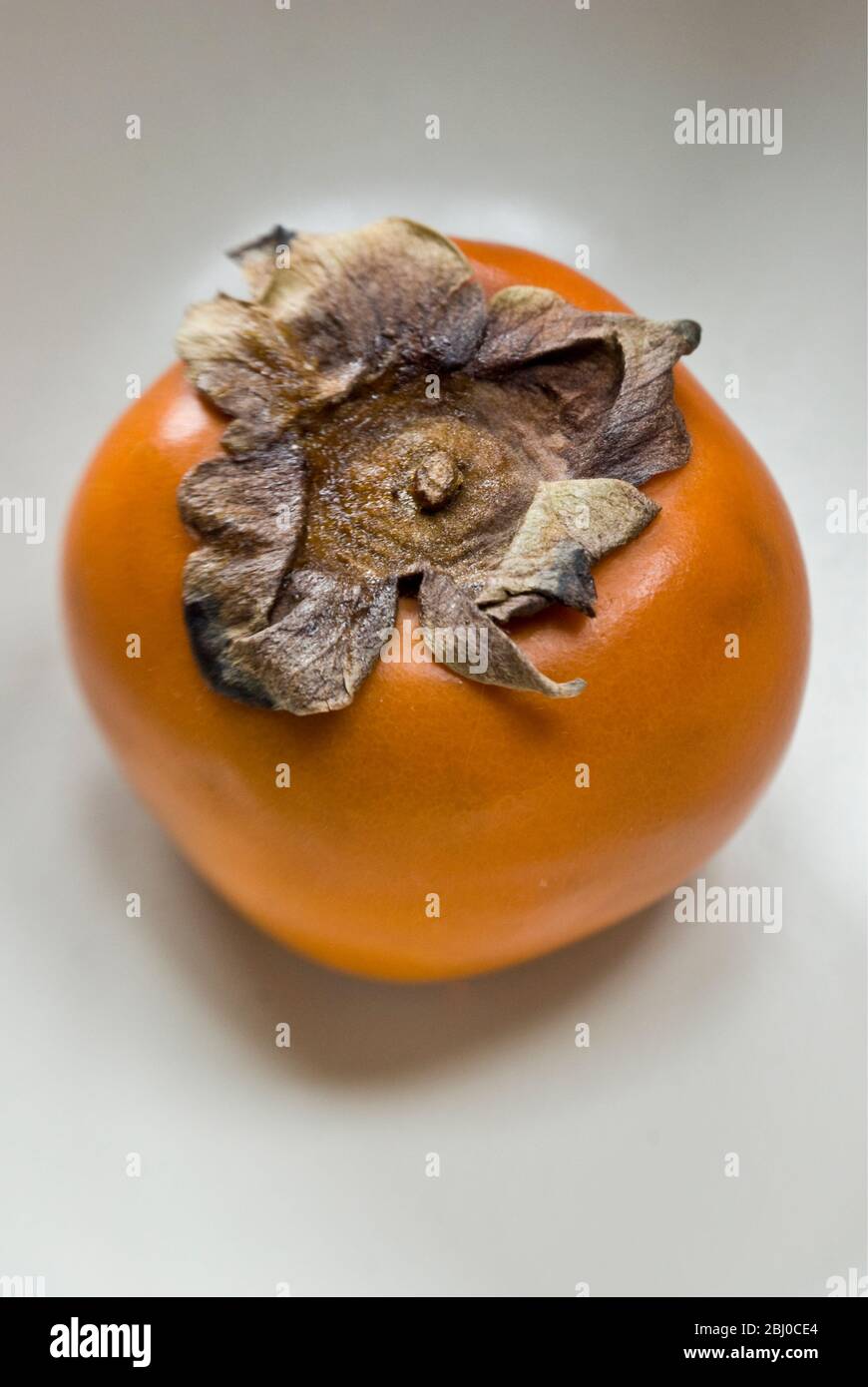 Einzelne rote Persimmon (sharon) Frucht auf dem Teller - Stockfoto