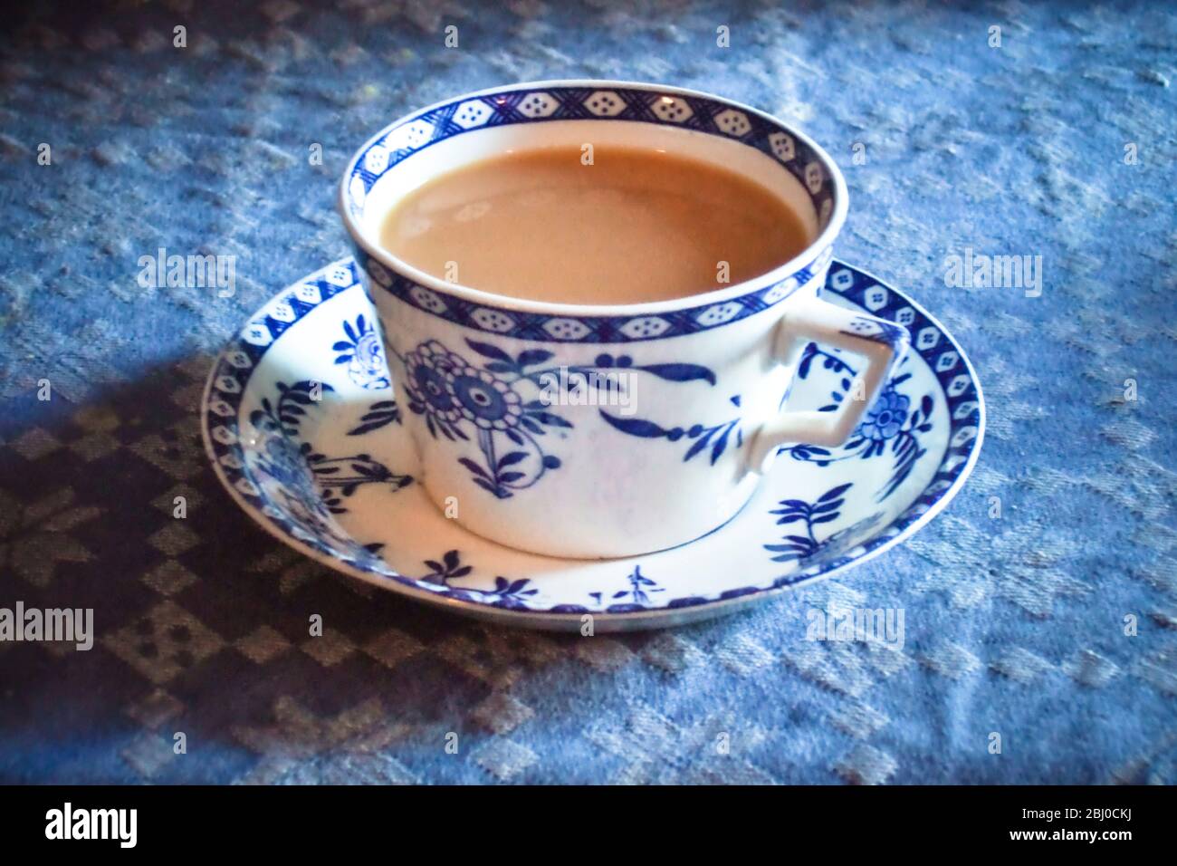 Antik blau und weiß Tasse und Untertasse von indischen Tee mit Milch, auf blauer Tischdecke - Stockfoto