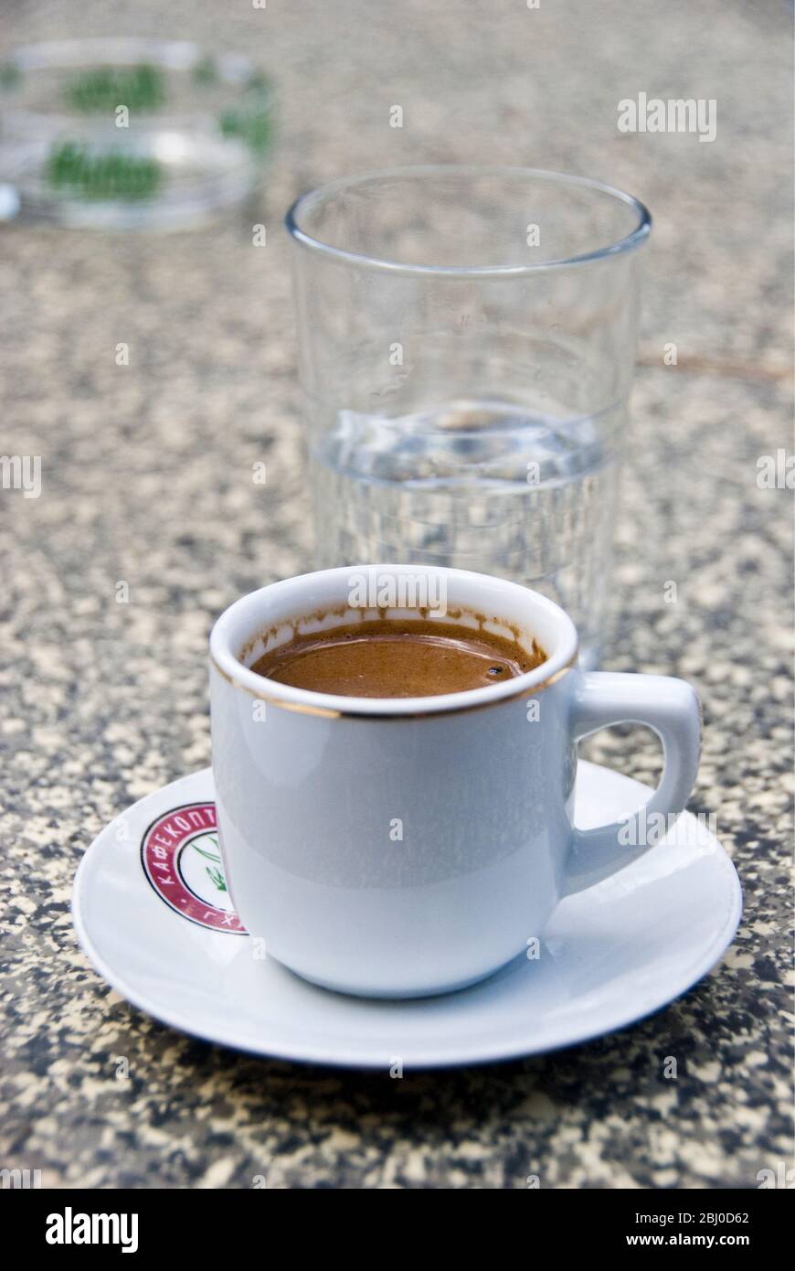 Griechischer Kaffee und ein Glas Wasser auf dem Tisch des Restaurants in den Hügeln Zyperns. - Stockfoto