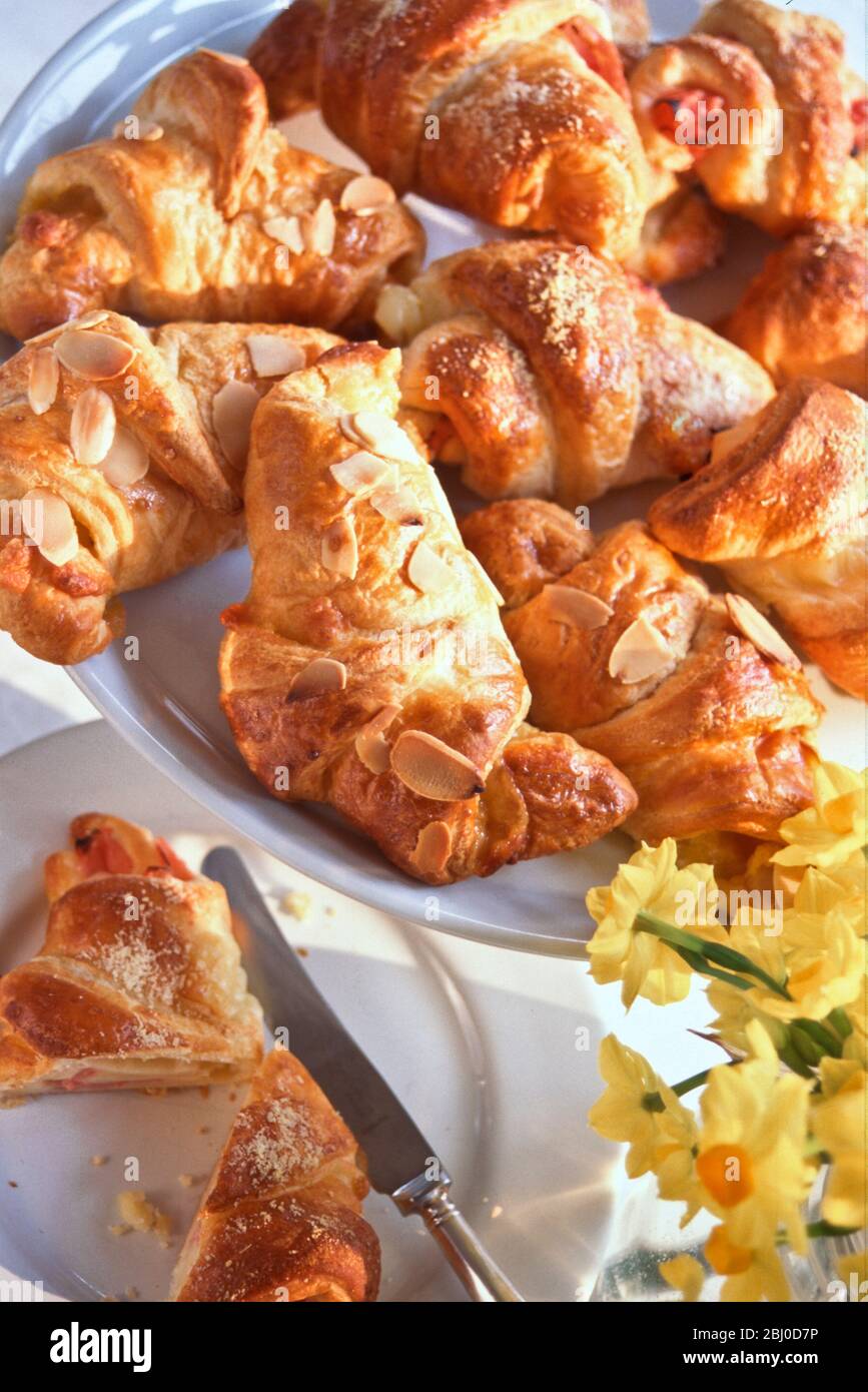Gericht mit kleinen Croissants, einige süß mit Mandeln geblätscht, einige herzhaft mit Schinken und Käse. - Stockfoto