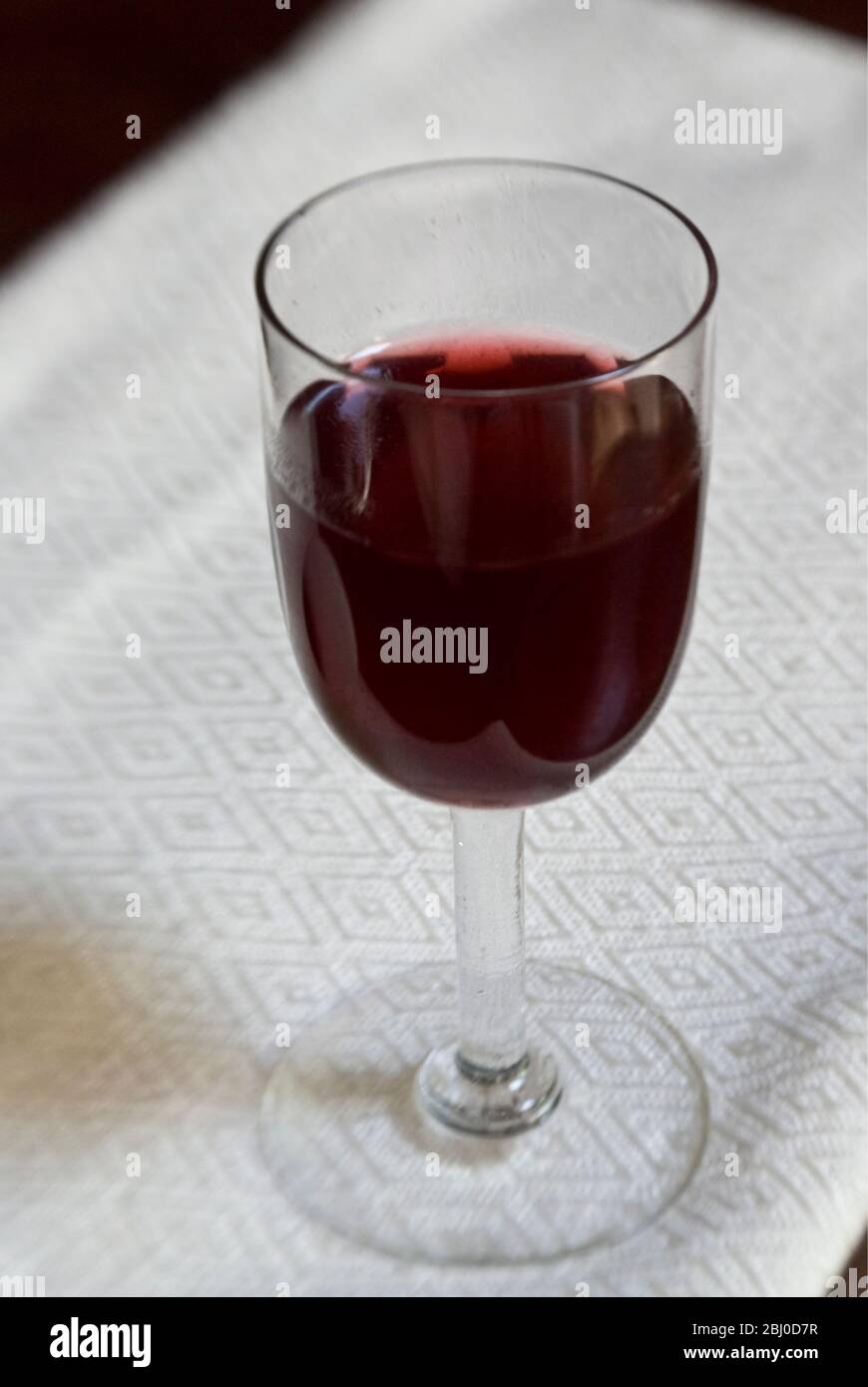 Ein Glas hausgemachten Schlehe Gin in kleinem Glas auf Leinentuch - Stockfoto