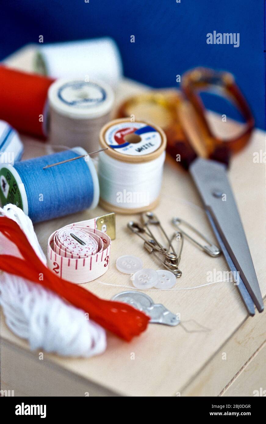 Verschiedene Teile Nähset, einschließlich Fäden, Nadeln und Scheren auf Holzkiste. - Stockfoto