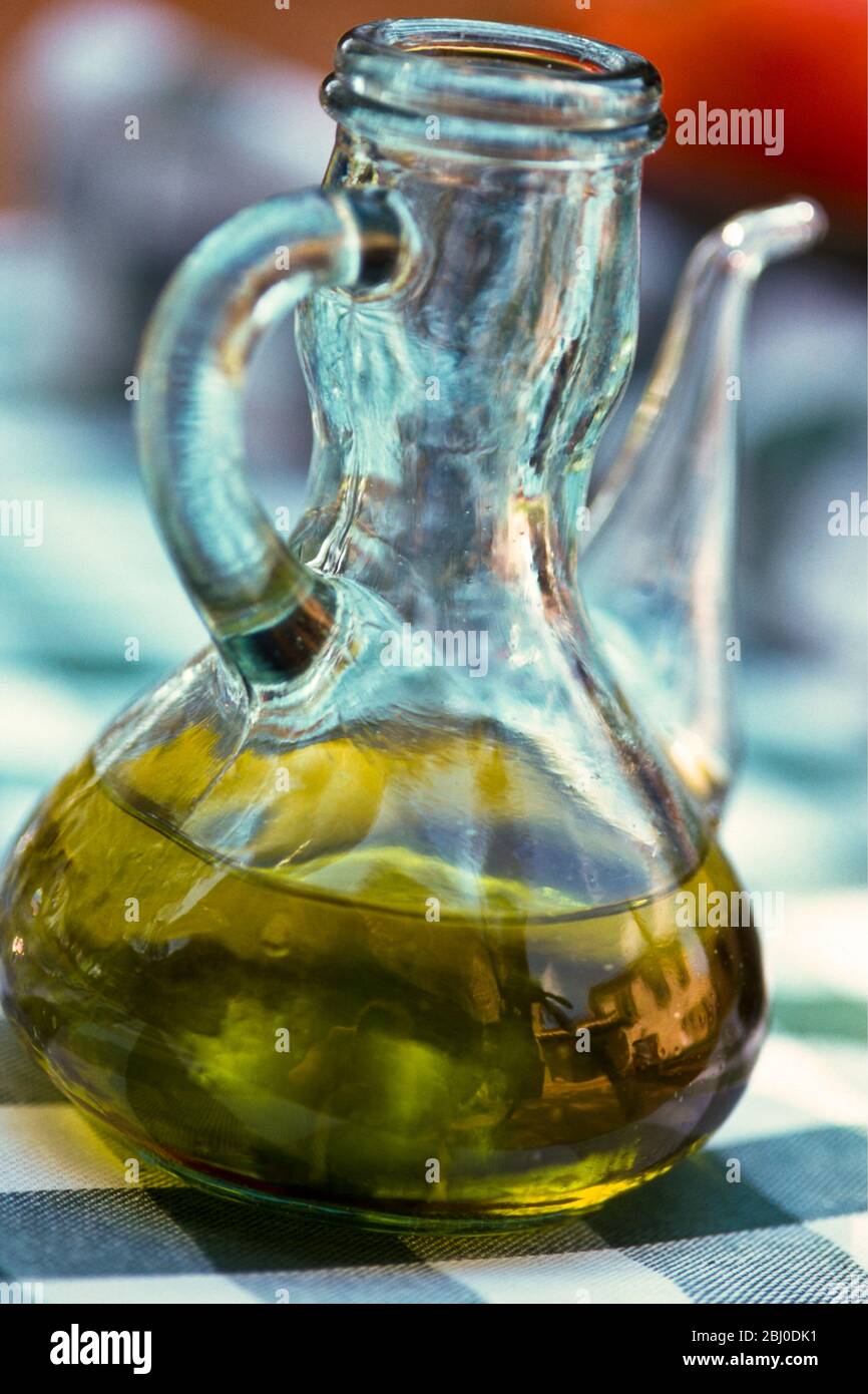 Flasche Olivenöl auf dem Tisch im Freien in Südfrankreich, mit Spiegelung des rosa Hauses - Stockfoto