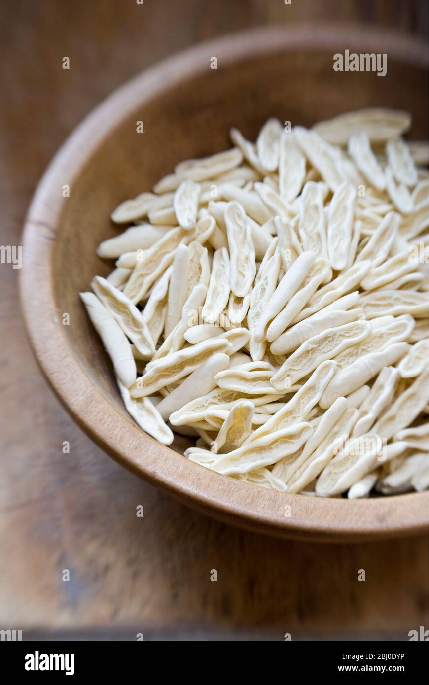 Rohe Cicatelli Pasta Formen, in alten Holzschale auf Holzfläche - Stockfoto