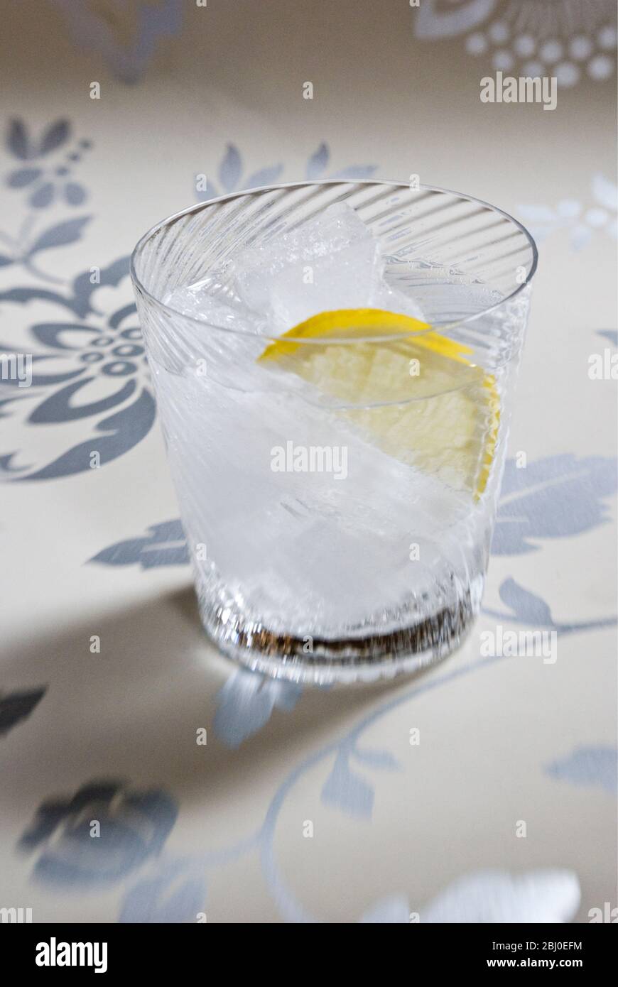 Feine Spirale geblasen Glas von klarem Geist mit Soda oder Tonic, und Scheibe Zitrone auf dekorativem Hintergrund - Stockfoto