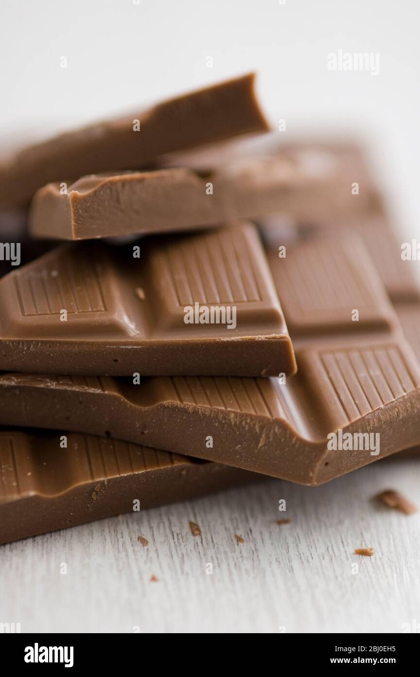 Stapel von gebrochenen Stücke von mik Schokolade Bar auf weißer Oberfläche. - Stockfoto