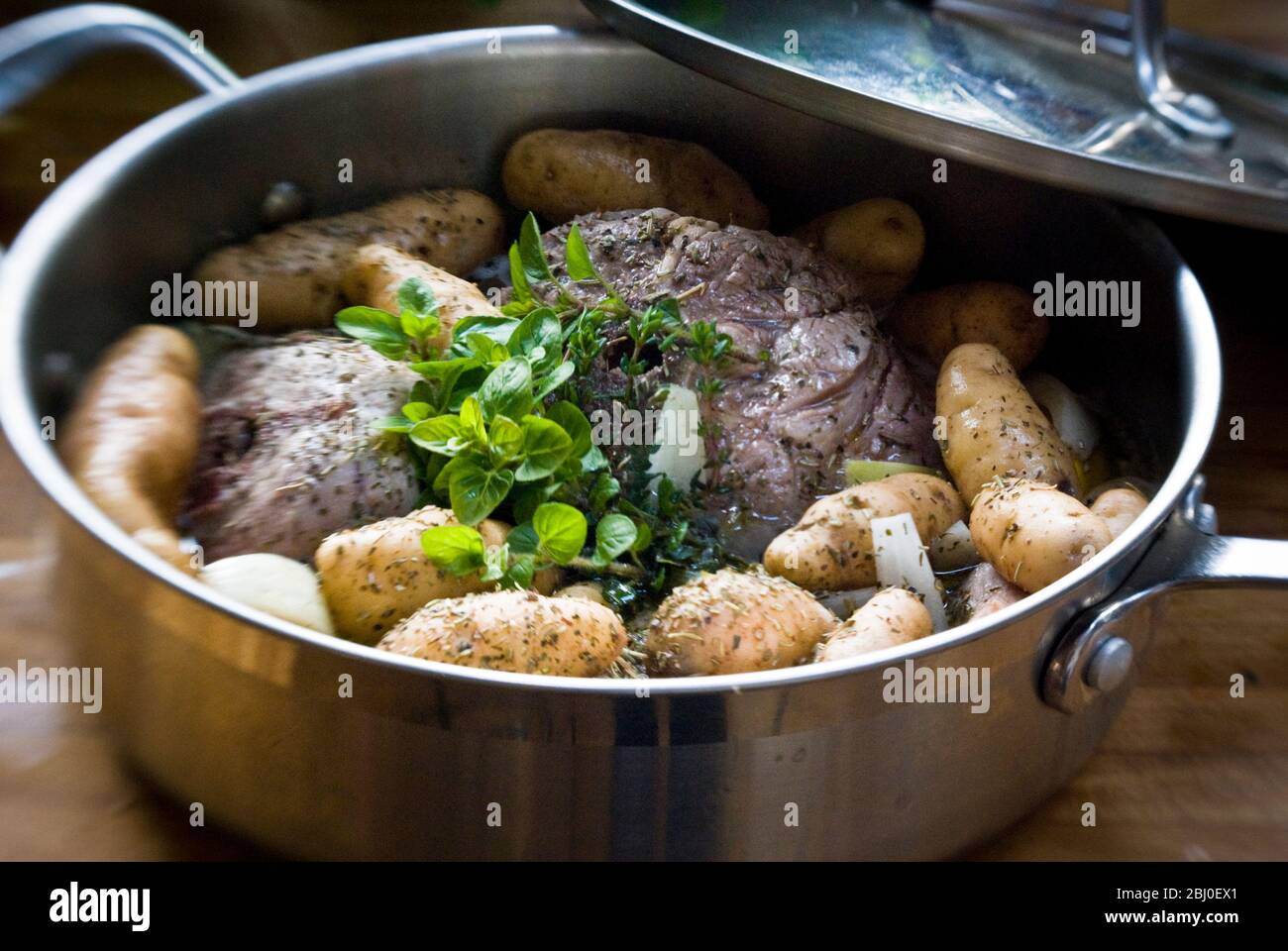 Lammhalsstücke mit Gewürzen und frischen Kräutern mit kleinen Anya-Kartoffeln in breiter Pfanne - Stockfoto